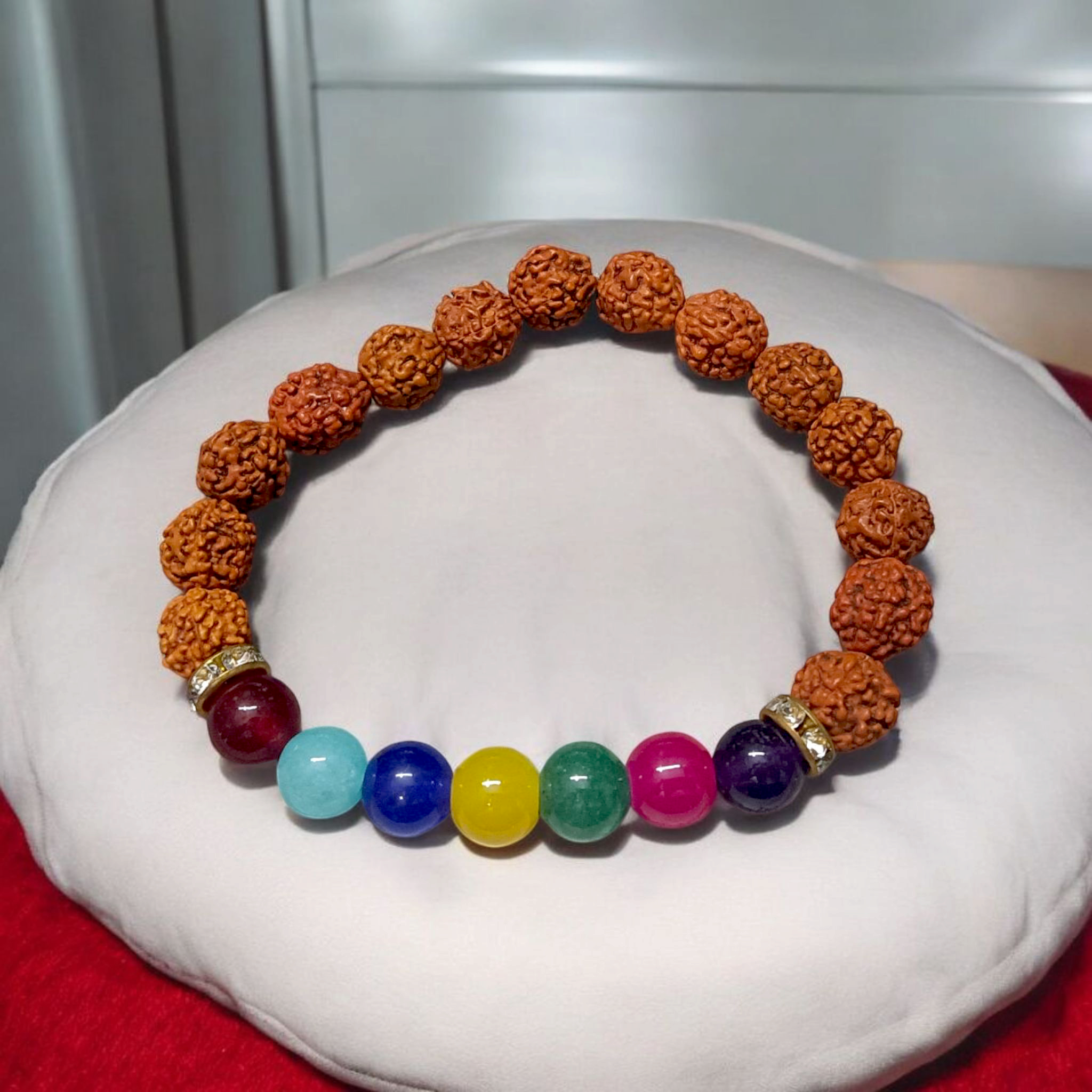 7 Chakra & Rudraksha Bracelet with 8mm natural beads, arranged in colorful chakra order alongside sacred Rudraksha beads, displayed on a spiritual setting