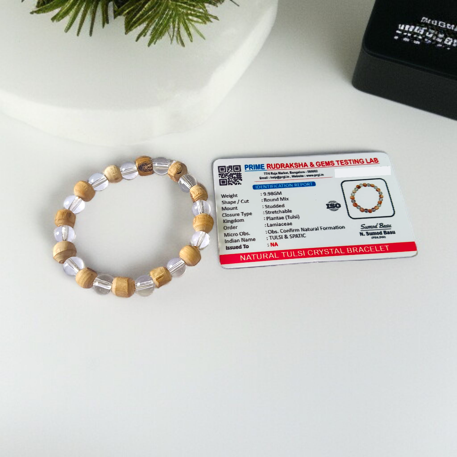 A Natural Tulsi and Sphatik crystal stretchable bracelet with 8mm beads, placed elegantly on a wooden surface, used for meditation and spiritual healing