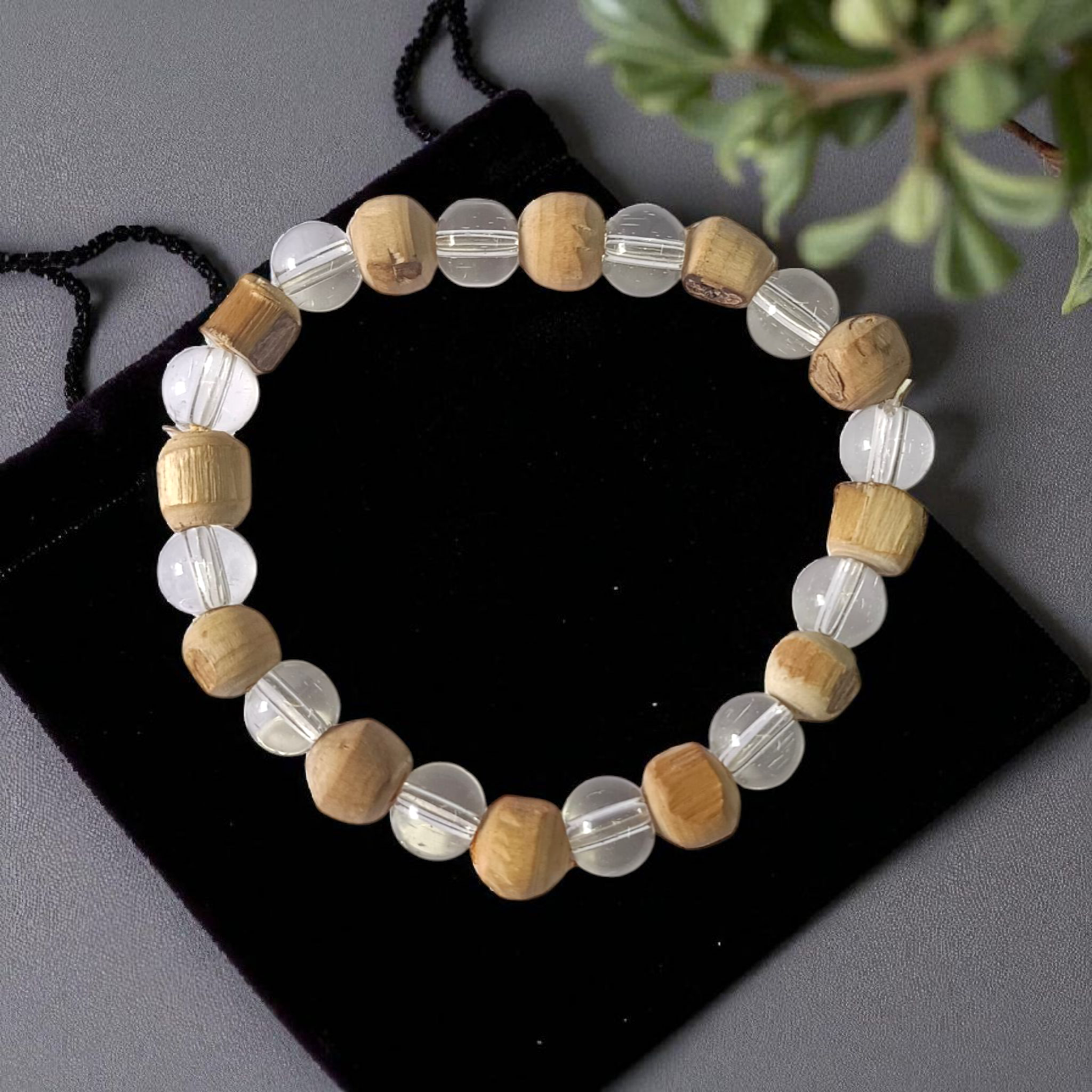 A Natural Tulsi and Sphatik crystal stretchable bracelet with 8mm beads, placed elegantly on a wooden surface, used for meditation and spiritual healing