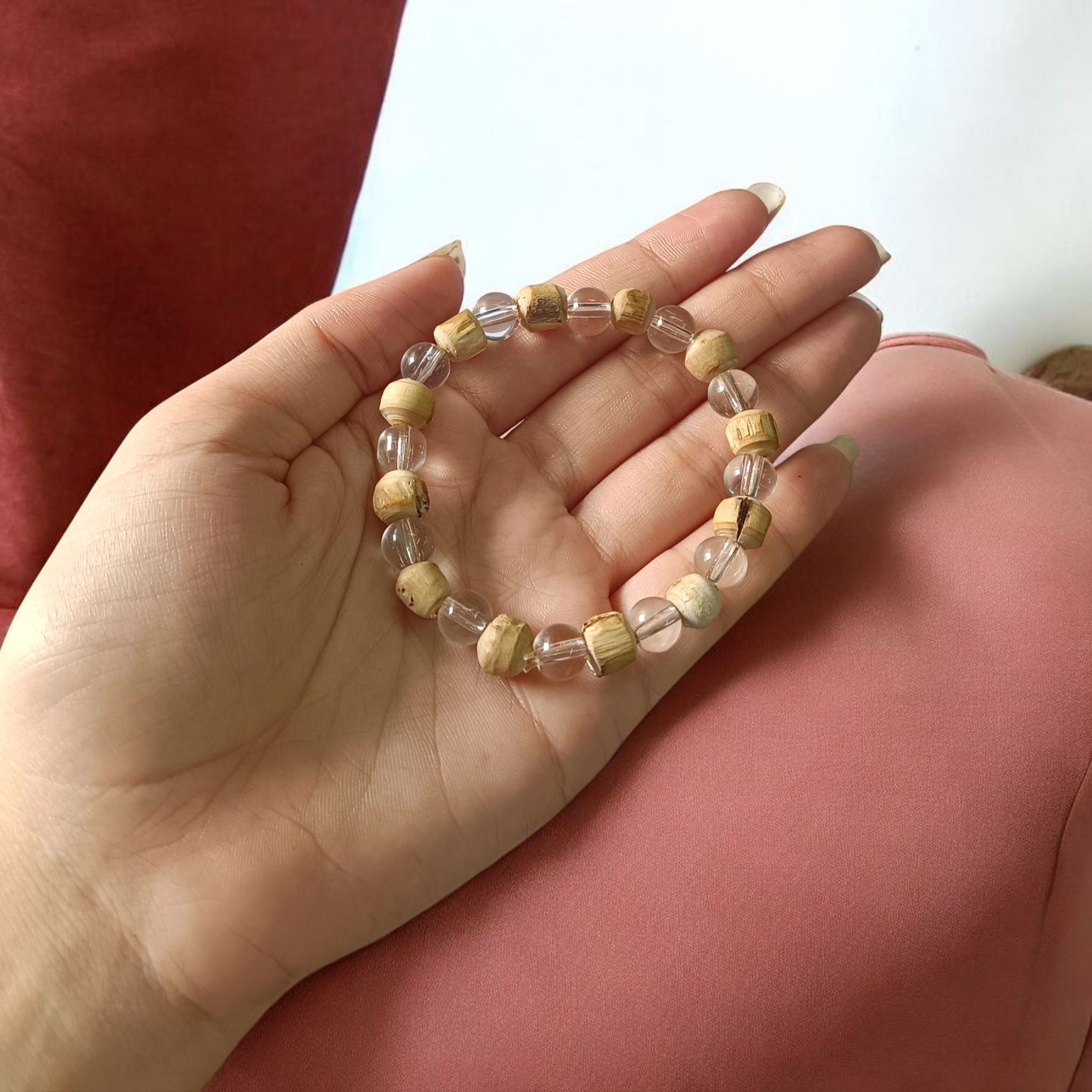 A Natural Tulsi and Sphatik crystal stretchable bracelet with 8mm beads, placed elegantly on a wooden surface, used for meditation and spiritual healing