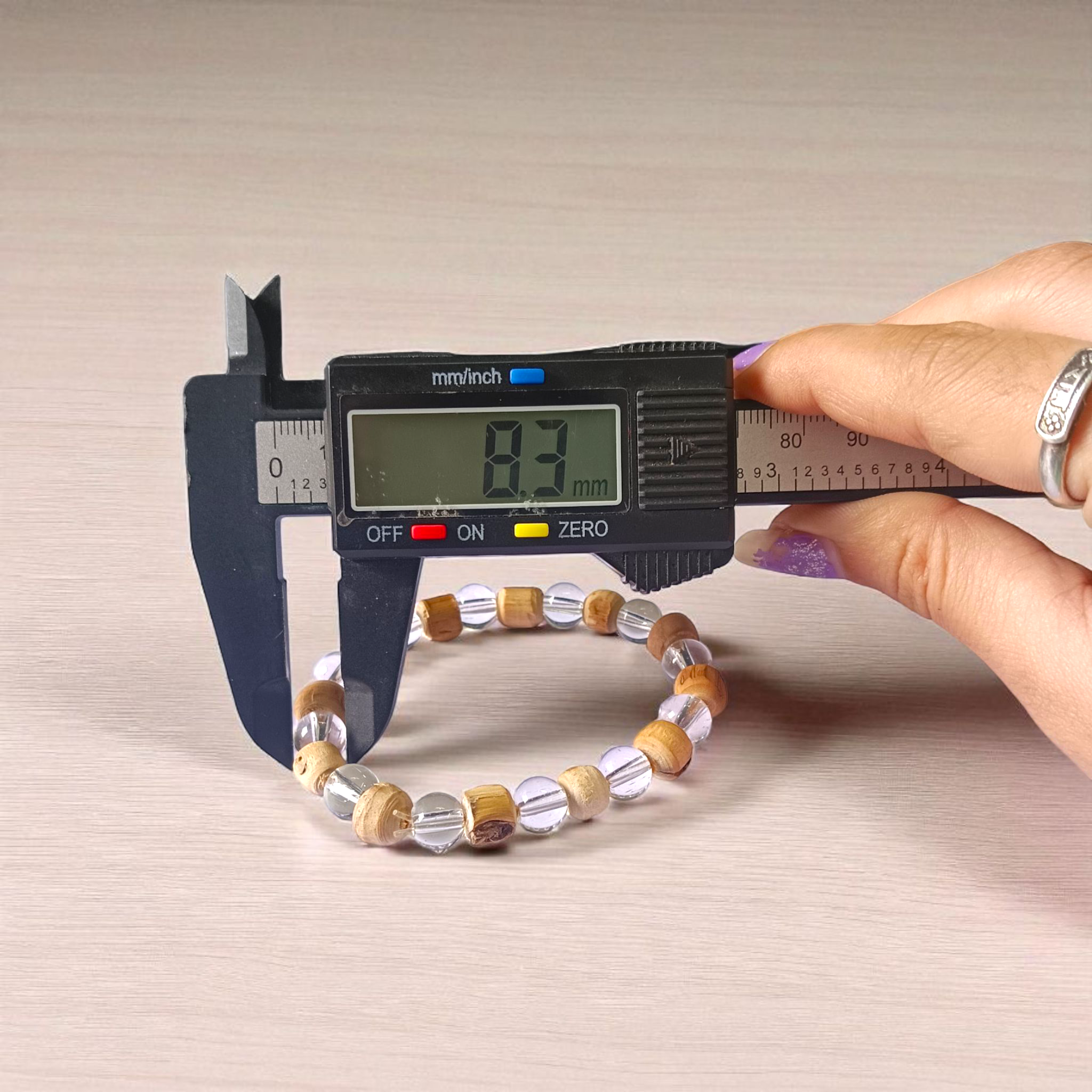 A Natural Tulsi and Sphatik crystal stretchable bracelet with 8mm beads, placed elegantly on a wooden surface, used for meditation and spiritual healing