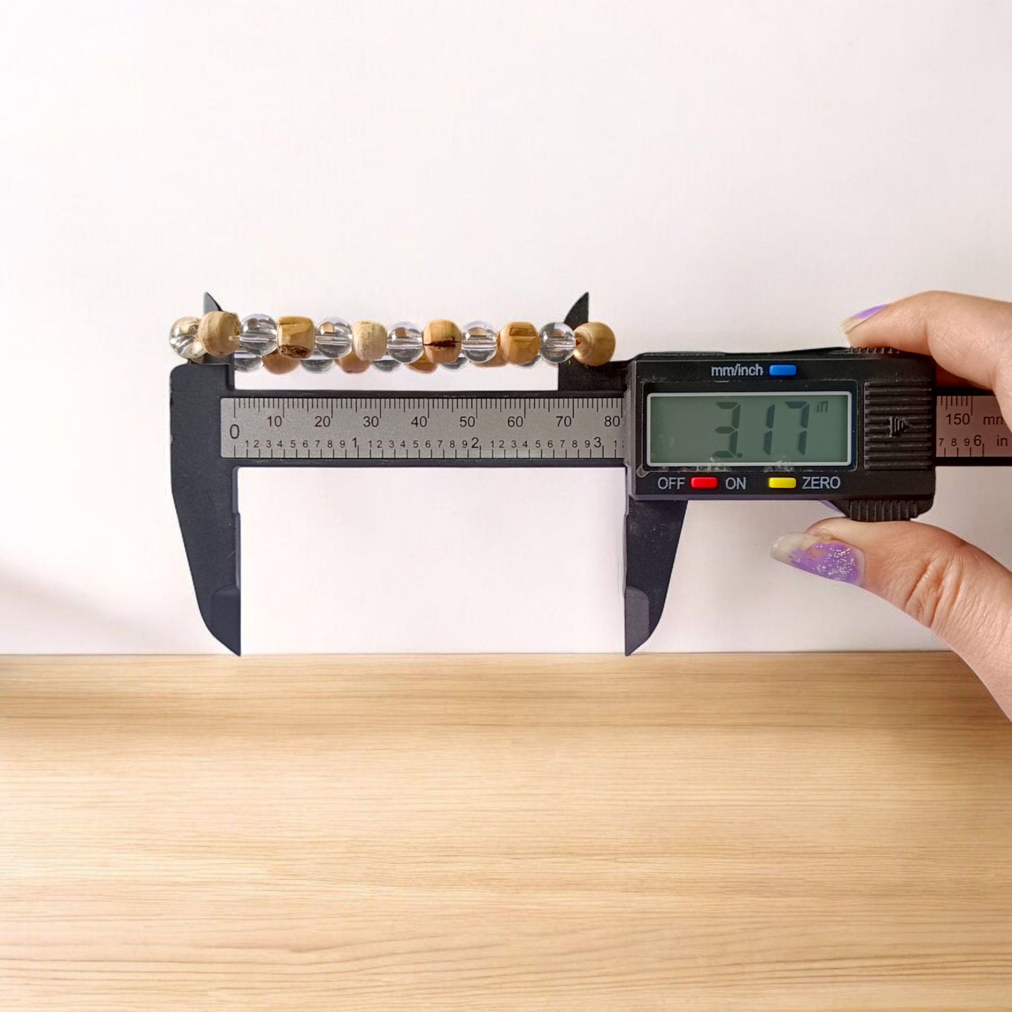 A Natural Tulsi and Sphatik crystal stretchable bracelet with 8mm beads, placed elegantly on a wooden surface, used for meditation and spiritual healing