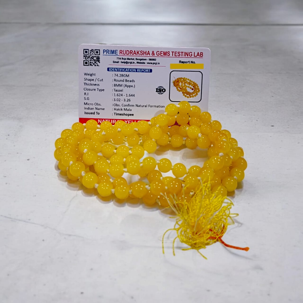 A Yellow Agate Mala with 8MM round beads in 108+1 bead count, hand-threaded and arranged neatly on a white surface, showcasing its golden hue and craftsmanship