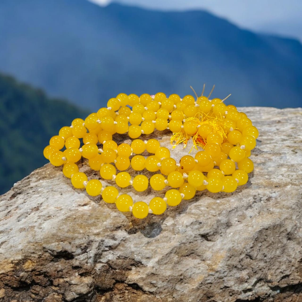 A Yellow Agate Mala with 8MM round beads in 108+1 bead count, hand-threaded and arranged neatly on a white surface, showcasing its golden hue and craftsmanship