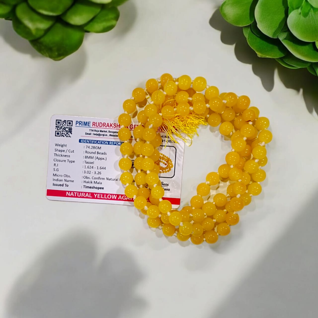 A Yellow Agate Mala with 8MM round beads in 108+1 bead count, hand-threaded and arranged neatly on a white surface, showcasing its golden hue and craftsmanship