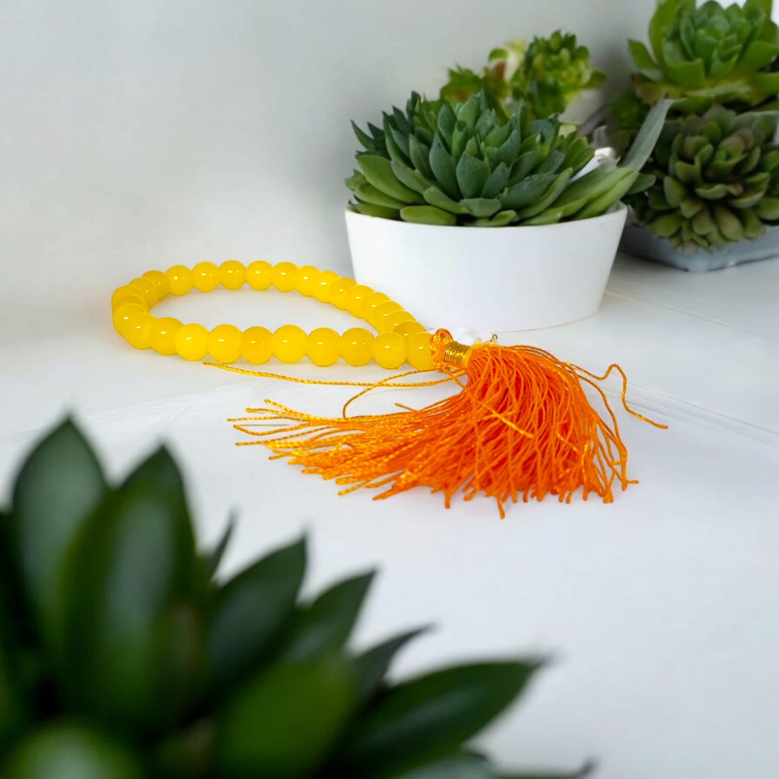 A Yellow Agate Mala with 8MM round beads in 108+1 bead count, hand-threaded and arranged neatly on a white surface, showcasing its golden hue and craftsmanship