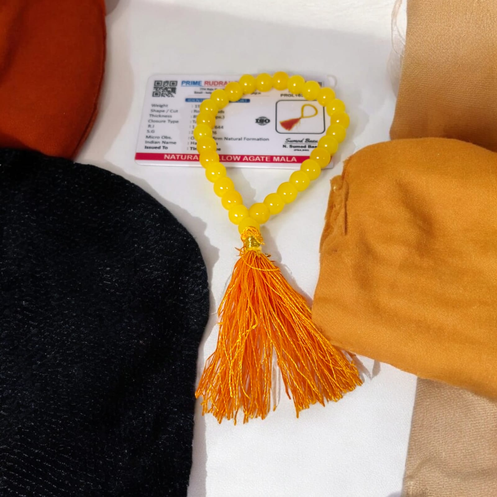 A Yellow Agate Mala with 8MM round beads in 108+1 bead count, hand-threaded and arranged neatly on a white surface, showcasing its golden hue and craftsmanship