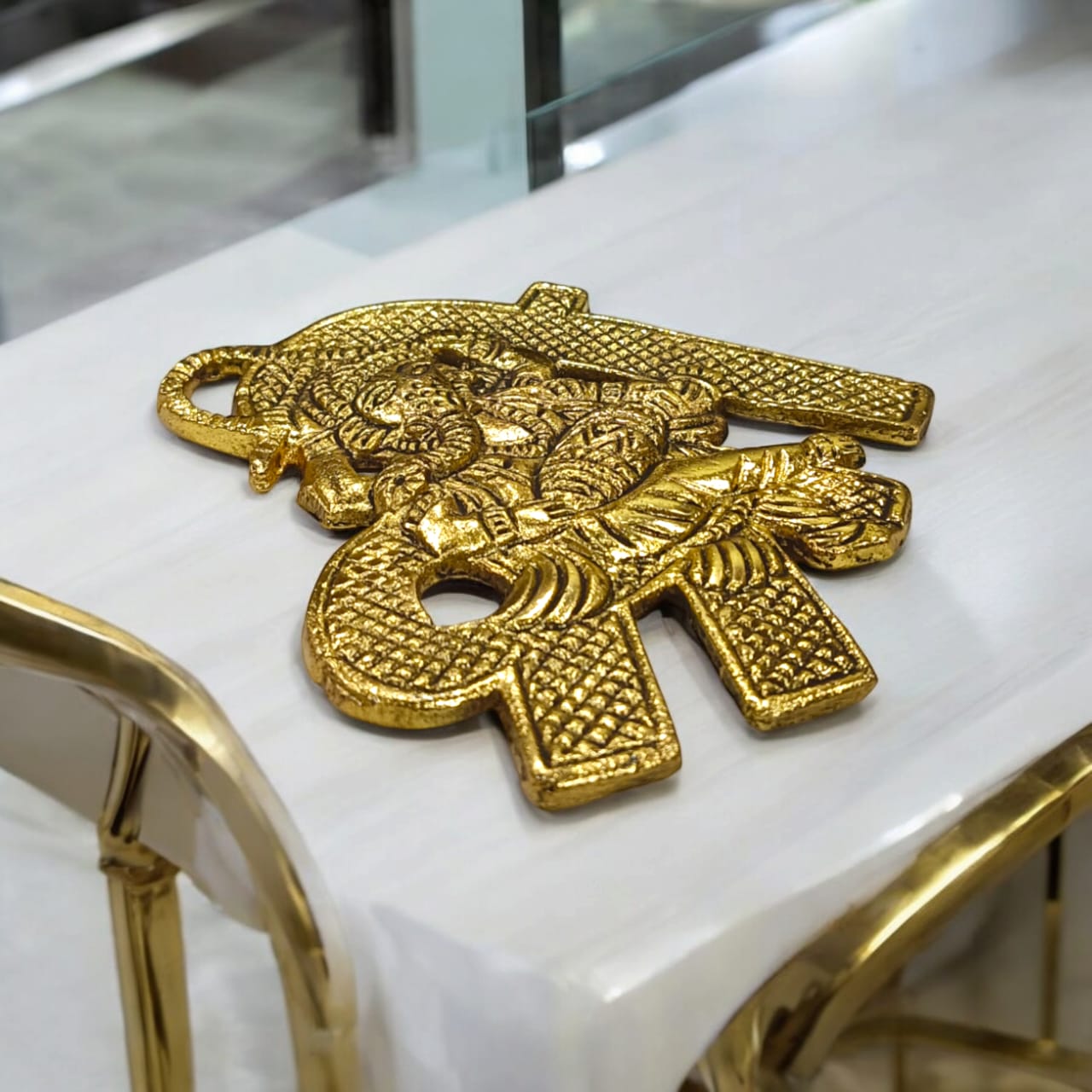 A beautifully crafted brass wall hanging of Shri Ganesh, measuring 11X11 CM, suitable for decorating temple walls, office spaces, and home doors.