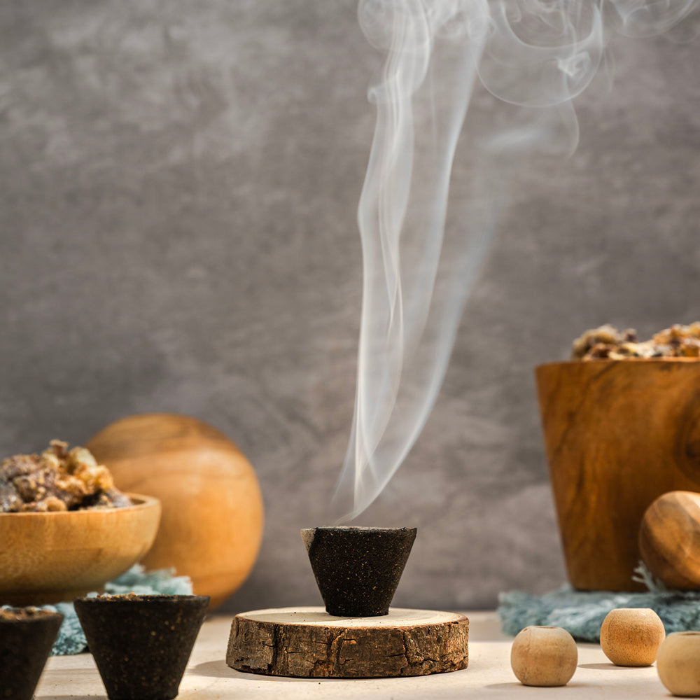 A box of Premium Cup Sambrani containing 12 natural dhoop cups arranged neatly, with herbal ingredients in the background
