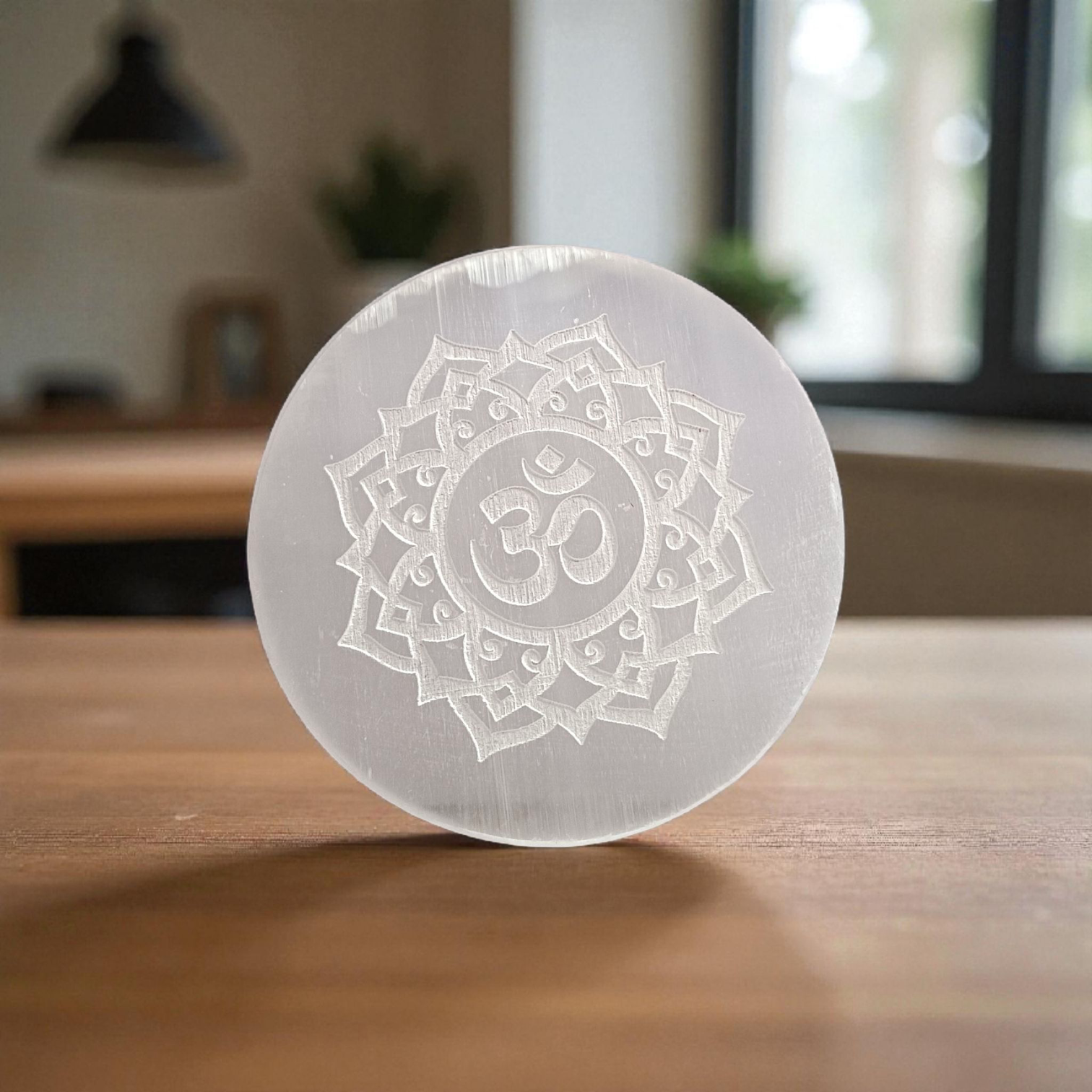 A polished round Selenite charging plate featuring a carved Om symbol, used for pooja, décor, and energy cleansing