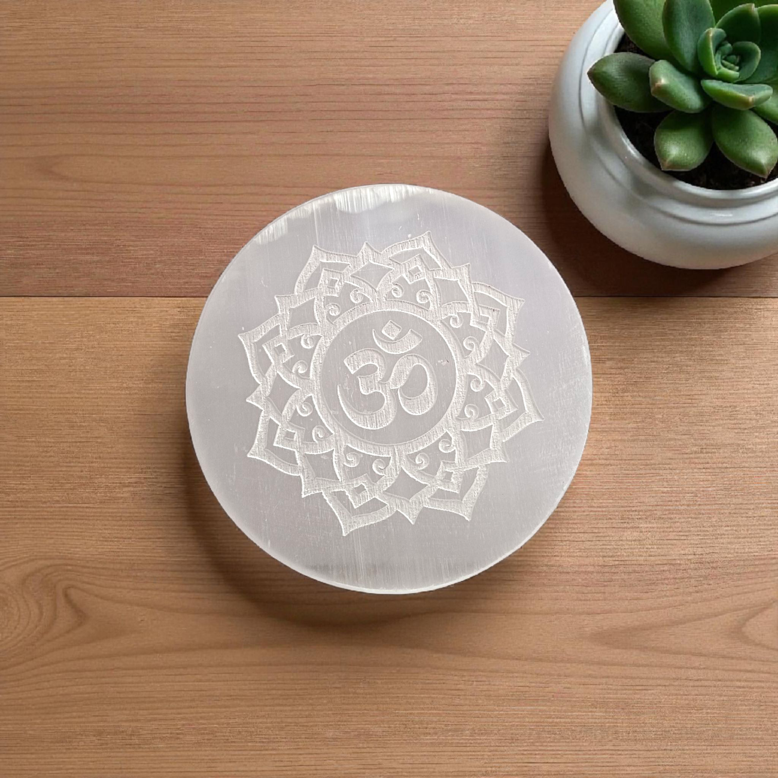 A polished round Selenite charging plate featuring a carved Om symbol, used for pooja, décor, and energy cleansing