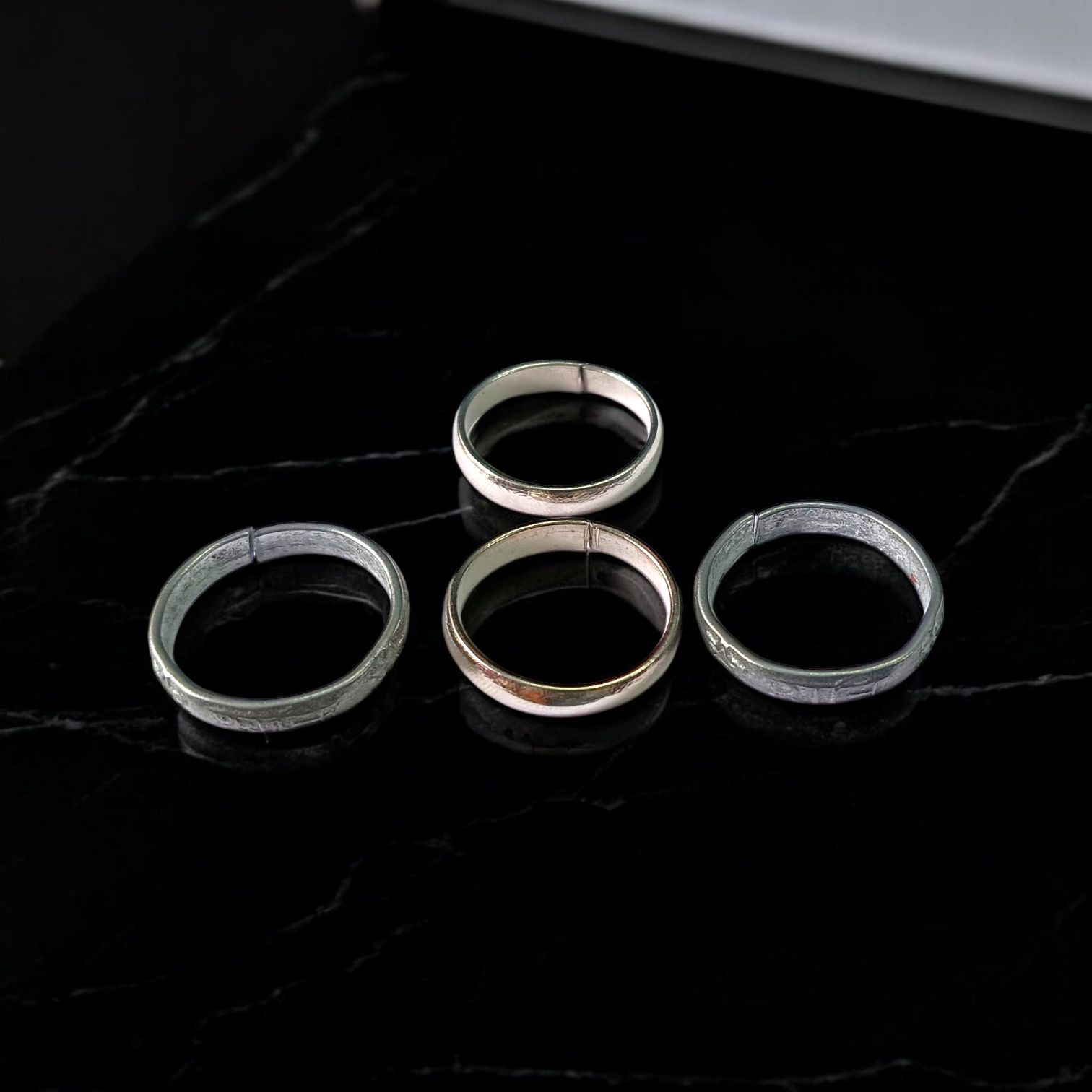 A set of four Ghode Ki Naal ka Challa rings made from black horse shoe nails, each ring designed to mitigate the negative effects of Saturn (Shani). The rings are shown in a close-up view to highlight their craftsmanship and material
