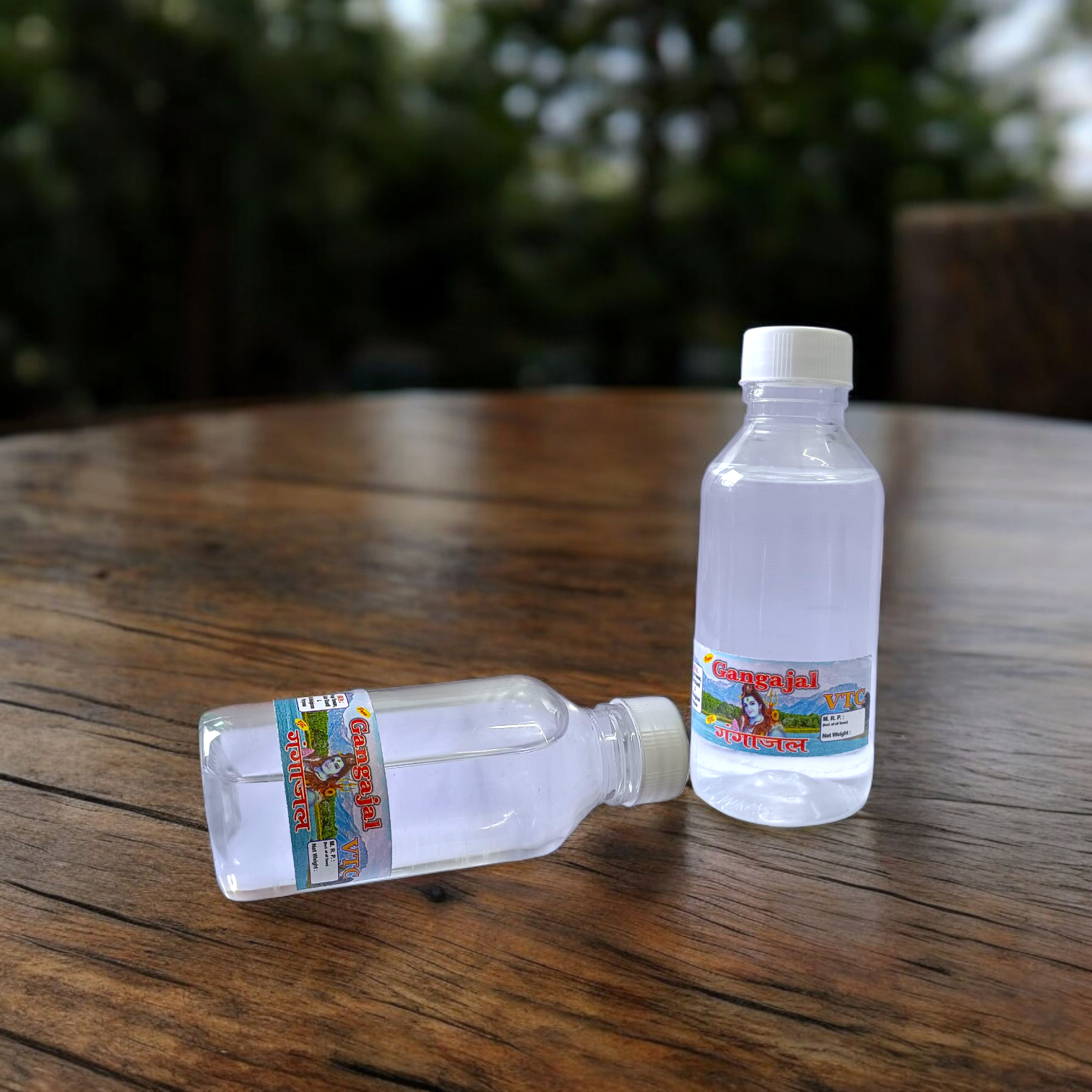 A set of two 100g bottles of Pure Gangajal Holy Water placed side by side, labeled for pooja and spiritual use