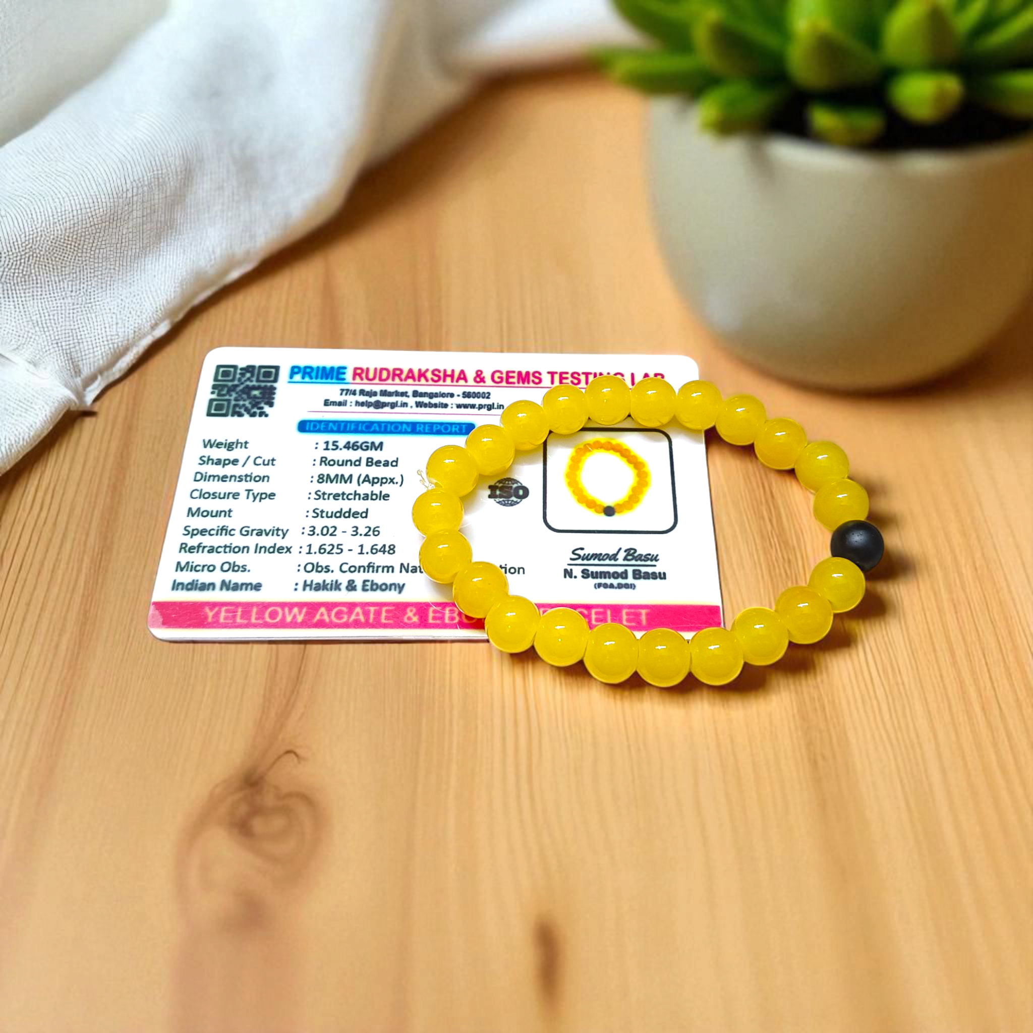 A stretchable Yellow Agate & Ebony Bracelet made with 8mm natural beads, placed neatly on a white cloth background