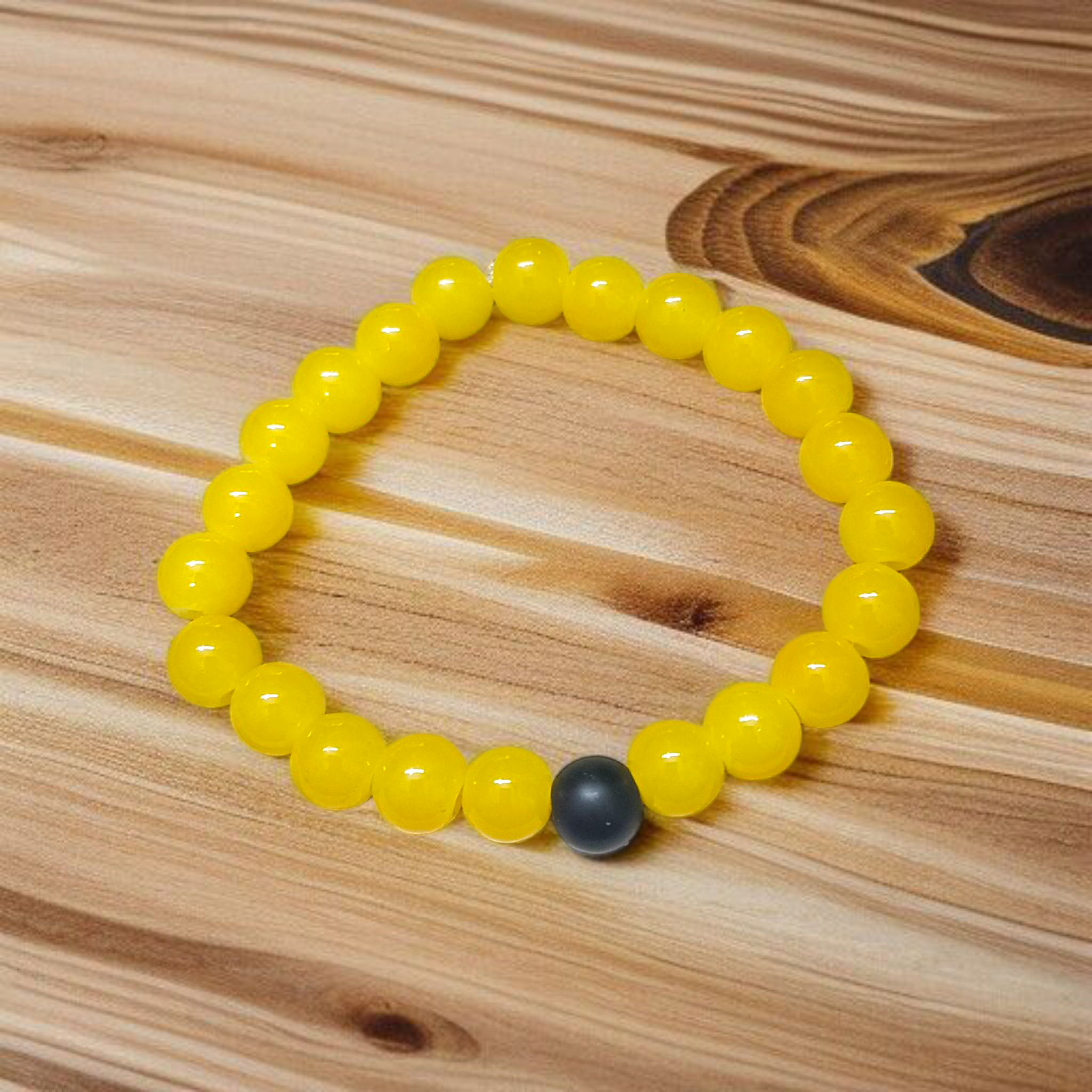 A stretchable Yellow Agate & Ebony Bracelet made with 8mm natural beads, placed neatly on a white cloth background