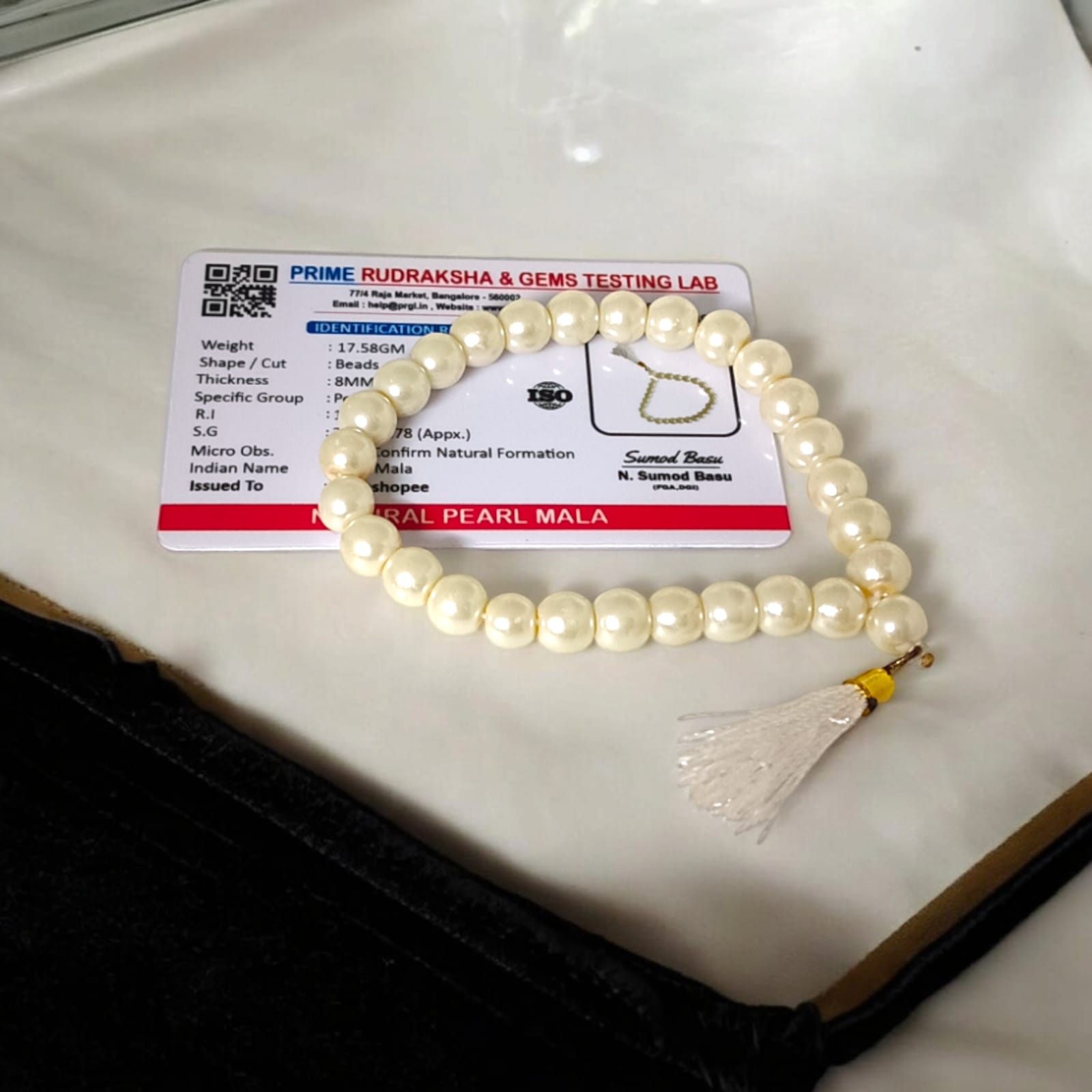 An elegant Pearl Mala featuring 27+1 original 8MM lab-certified pearls, arranged neatly for display.