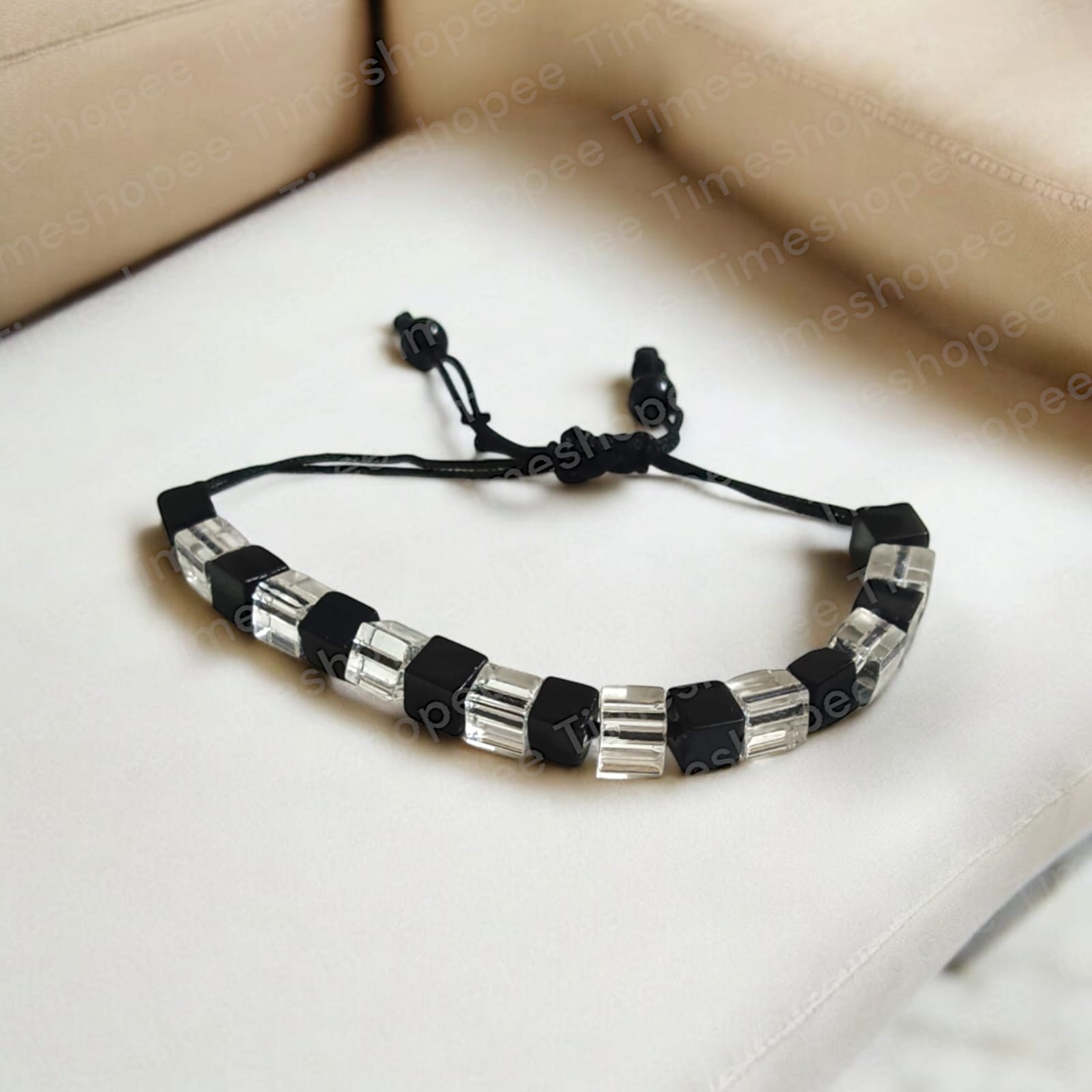 Black and white crystal bracelet with an evil eye symbol, featuring an adjustable thread for a customizable fit, designed for attraction and protection.