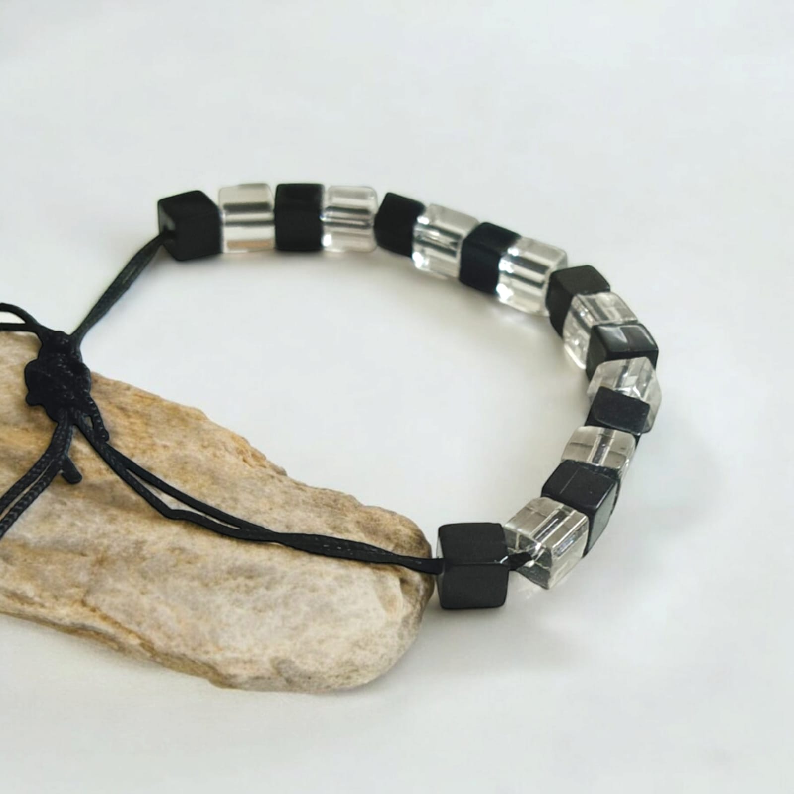 Black and white crystal bracelet with an evil eye symbol, featuring an adjustable thread for a customizable fit, designed for attraction and protection.
