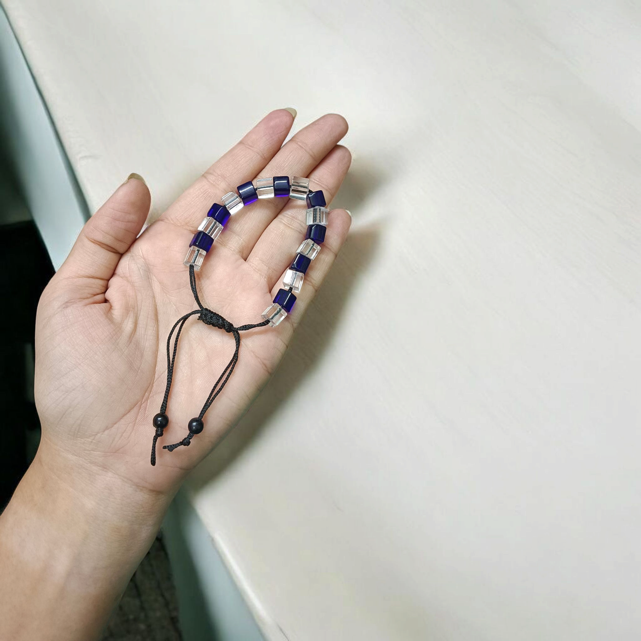 Blue and white crystal bracelet showcasing adjustable thread for a custom fit, designed to enhance personal attraction.