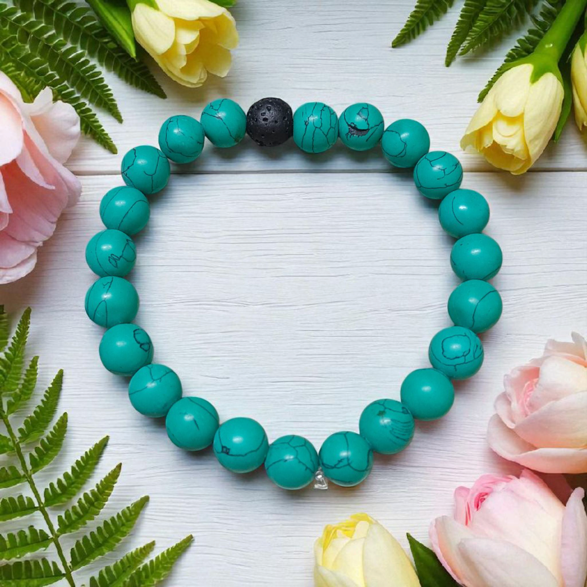 Bracelet made of 8mm natural turquoise and black lava stone beads, arranged on stretchable thread and displayed on a minimal, clean background