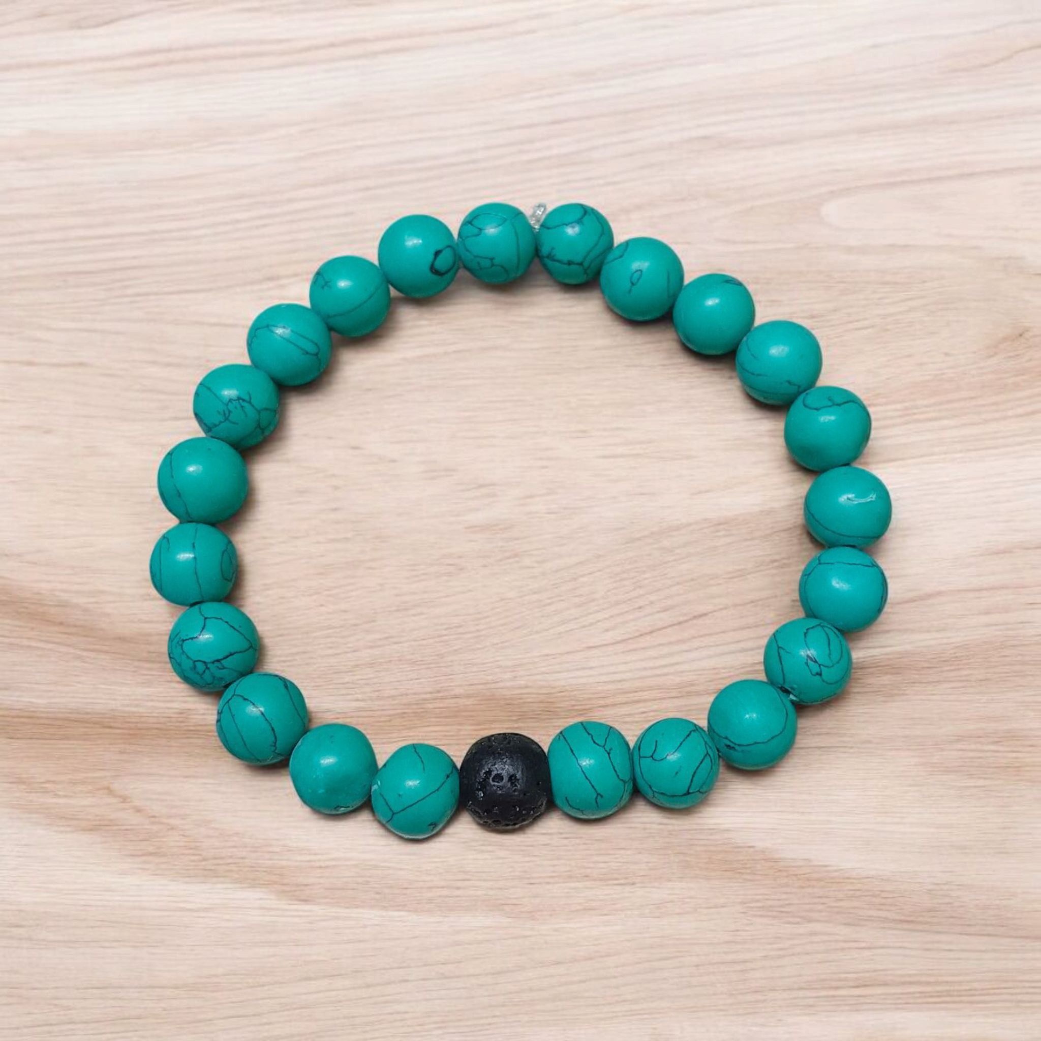 Bracelet made of 8mm natural turquoise and black lava stone beads, arranged on stretchable thread and displayed on a minimal, clean background