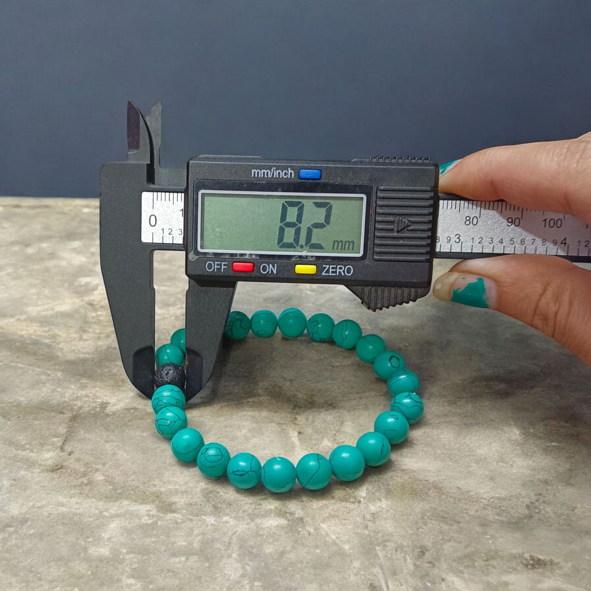 Bracelet made of 8mm natural turquoise and black lava stone beads, arranged on stretchable thread and displayed on a minimal, clean background