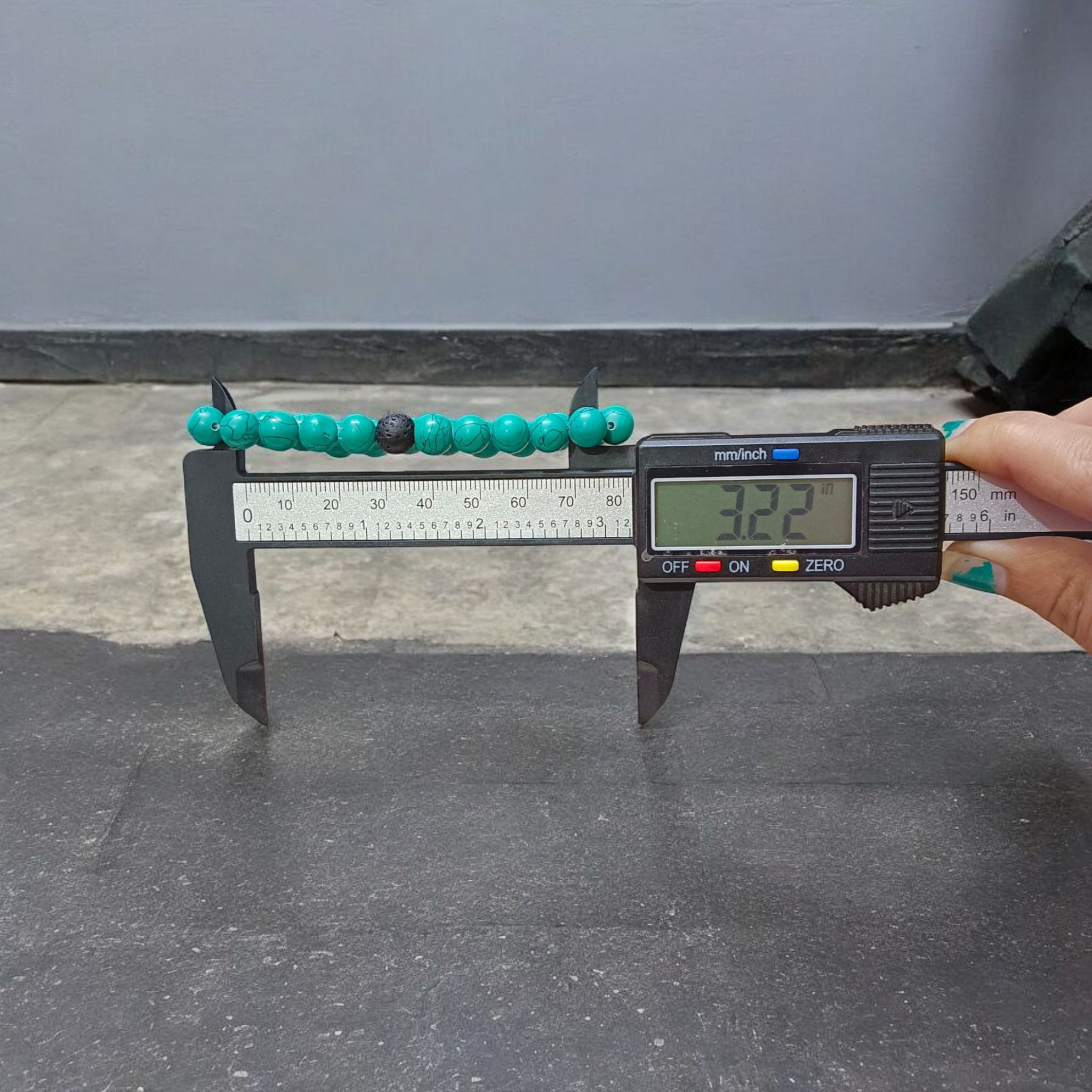 Bracelet made of 8mm natural turquoise and black lava stone beads, arranged on stretchable thread and displayed on a minimal, clean background