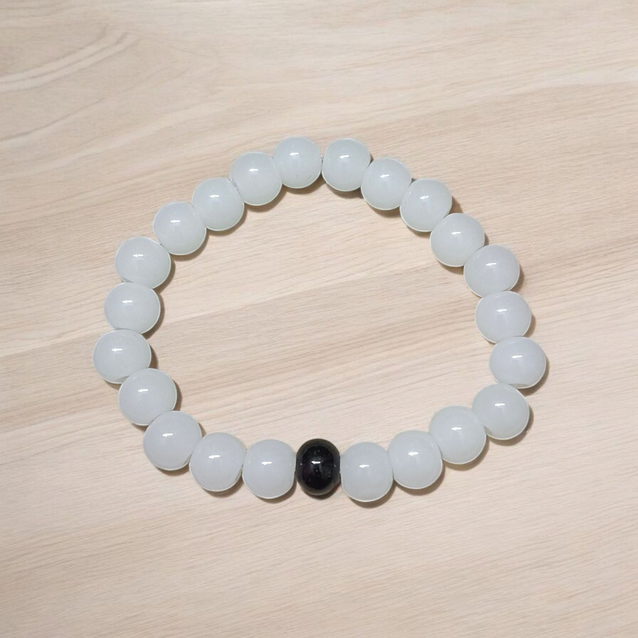Bracelet made of 8mm natural white and black agate beads arranged on a stretchable thread, displayed on a neutral surface
