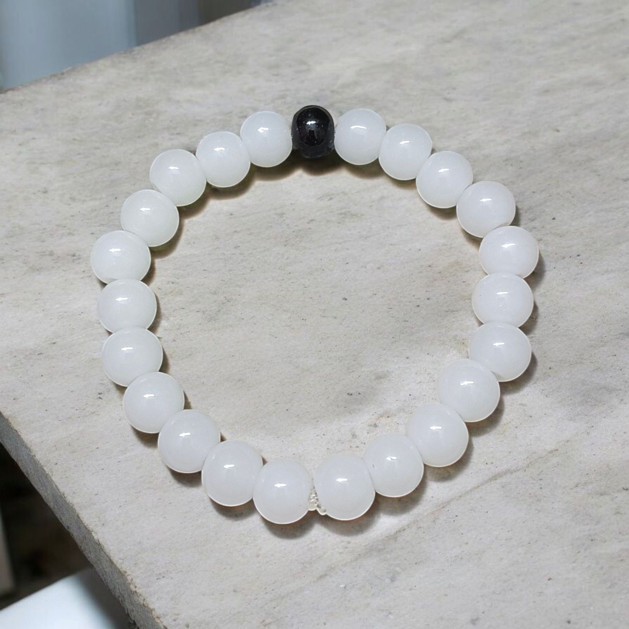 Bracelet made of 8mm natural white and black agate beads arranged on a stretchable thread, displayed on a neutral surface
