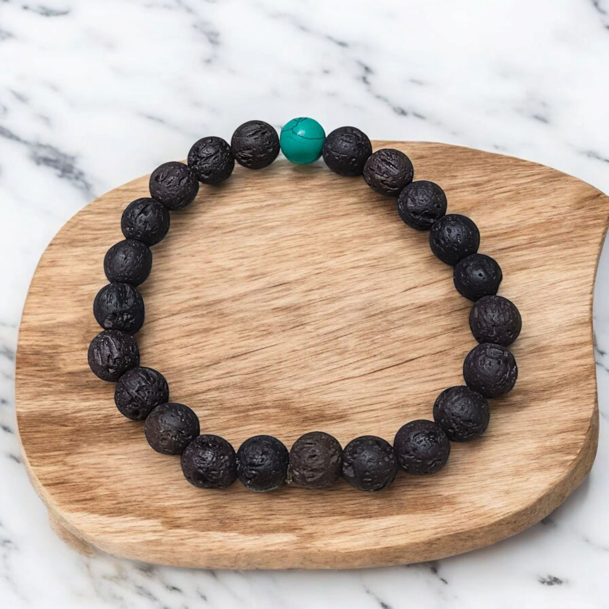 Bracelet made with 8mm black lava stones and turquoise (Firoza) beads, arranged on stretchable thread and placed on a soft neutral background