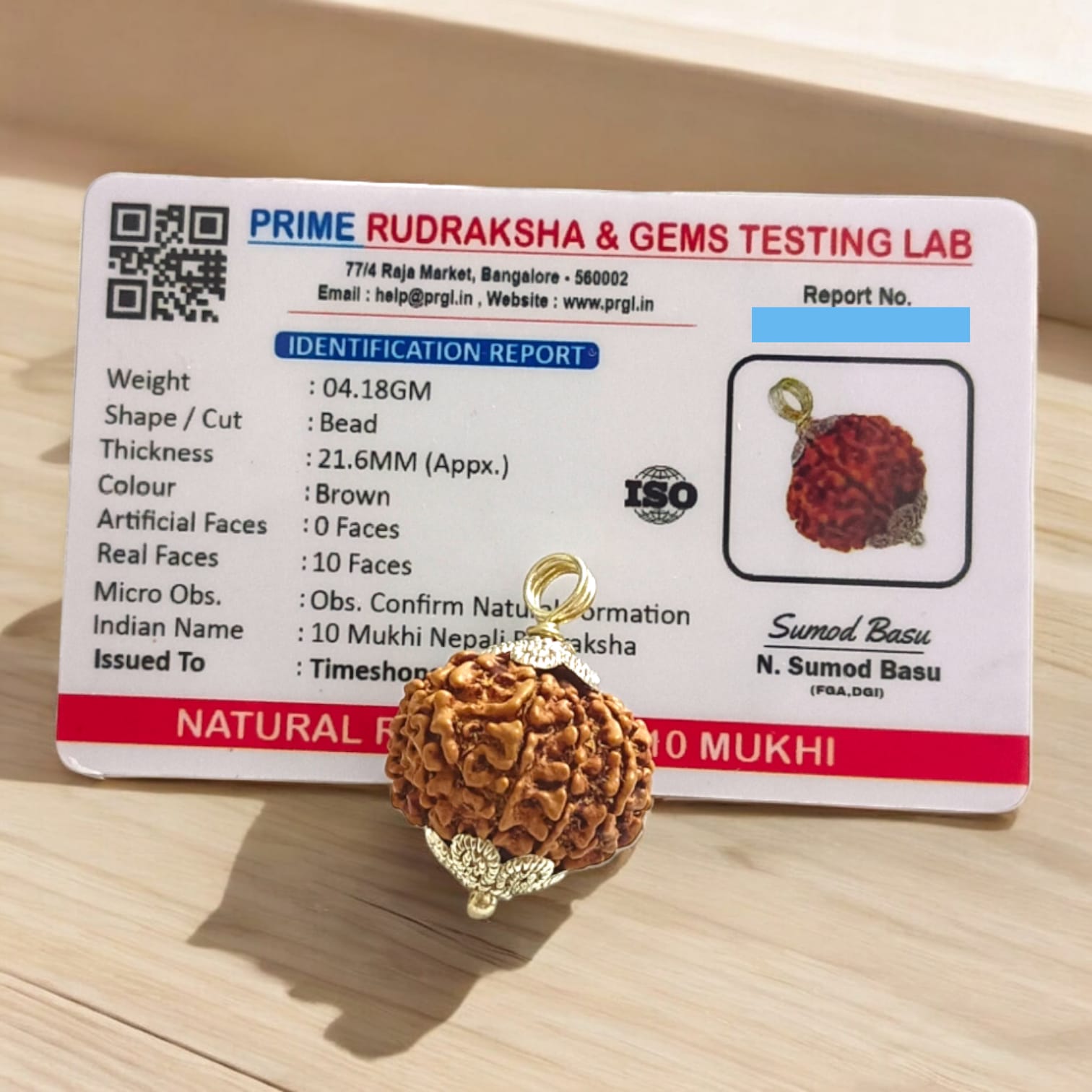 Close-up image of a lab-certified, original 10 Mukhi Rudraksha bead with clear natural grooves, placed on a wooden surface