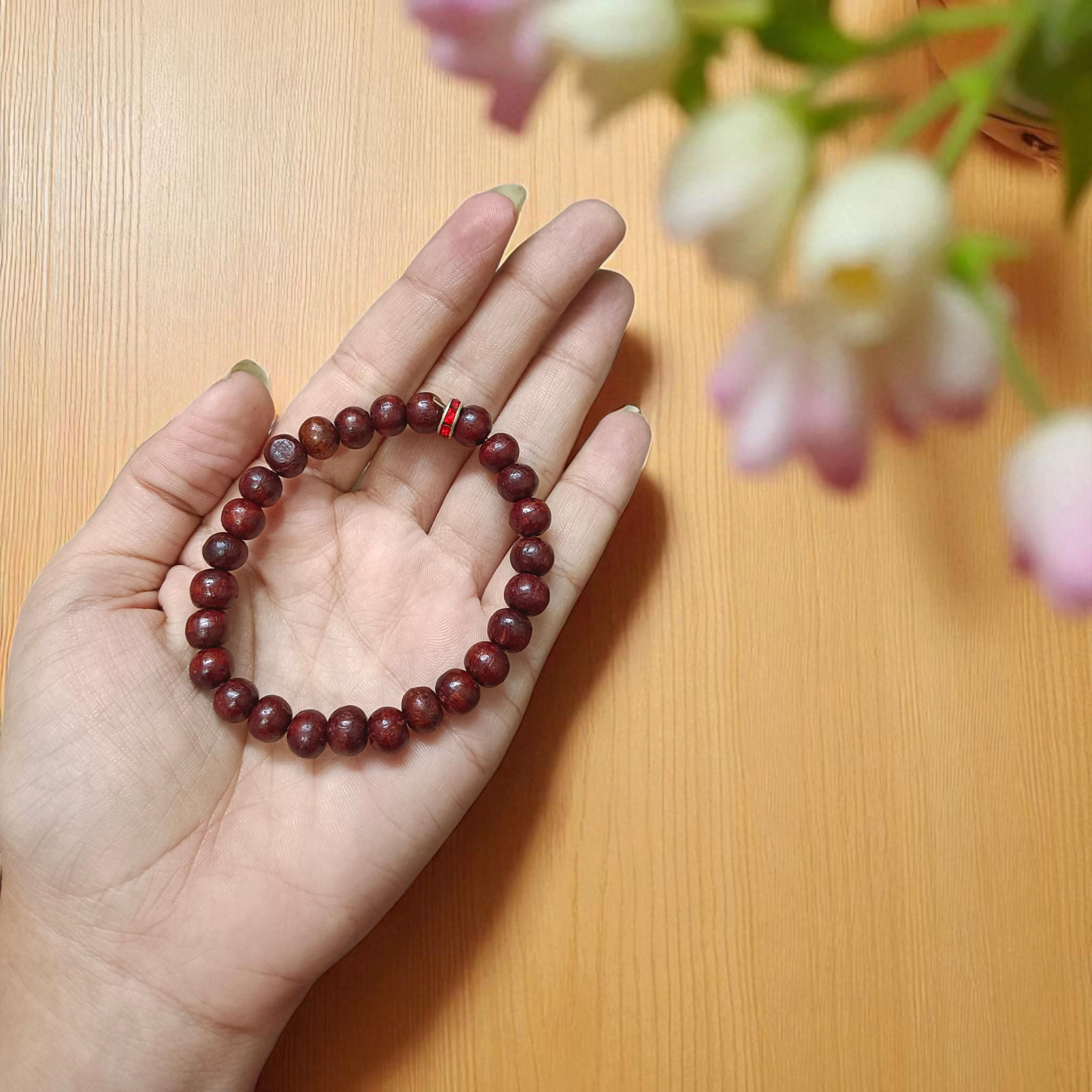 Image of a stretchable bracelet made with 8mm natural red sandalwood (Lal Chandan) beads, neatly arranged on a flat neutral background
