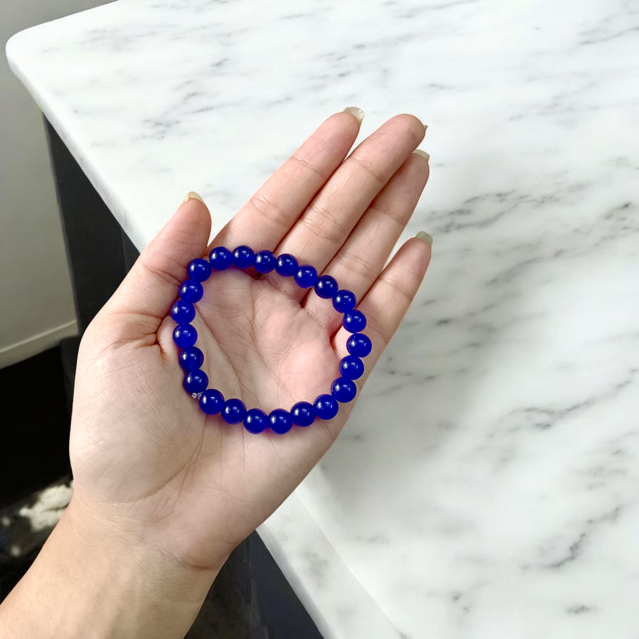 Natural Blue Agate (Hakik) Bracelet with 8mm round beads on a stretchable elastic cord, displayed in hand for spiritual and daily wear