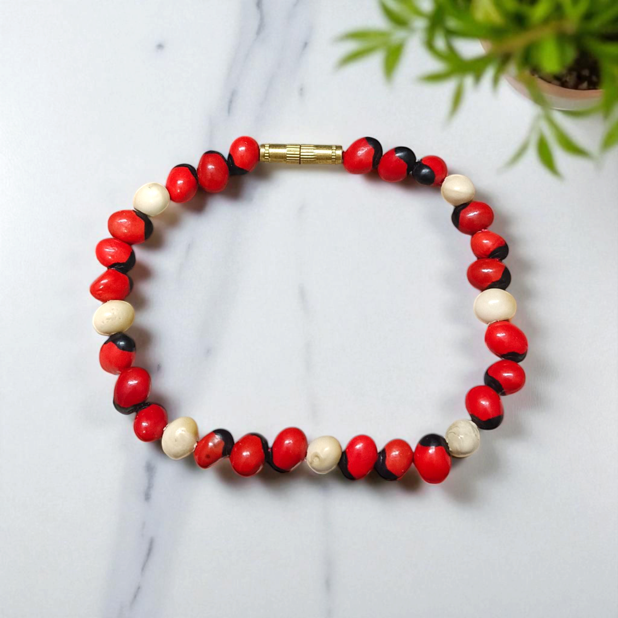 Natural Red and White Gunja seed bracelet with 5mm stretchable beads, spiritual design laid on a neutral background