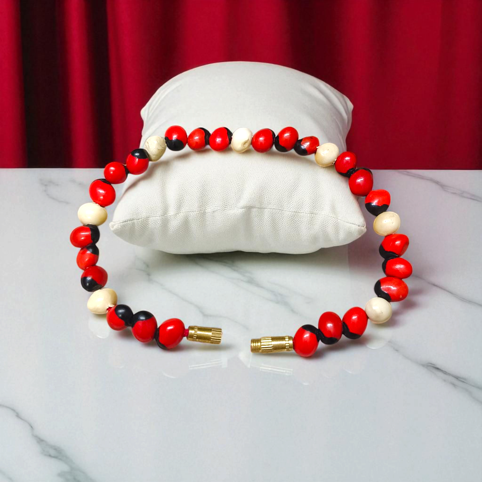 Natural Red and White Gunja seed bracelet with 5mm stretchable beads, spiritual design laid on a neutral background