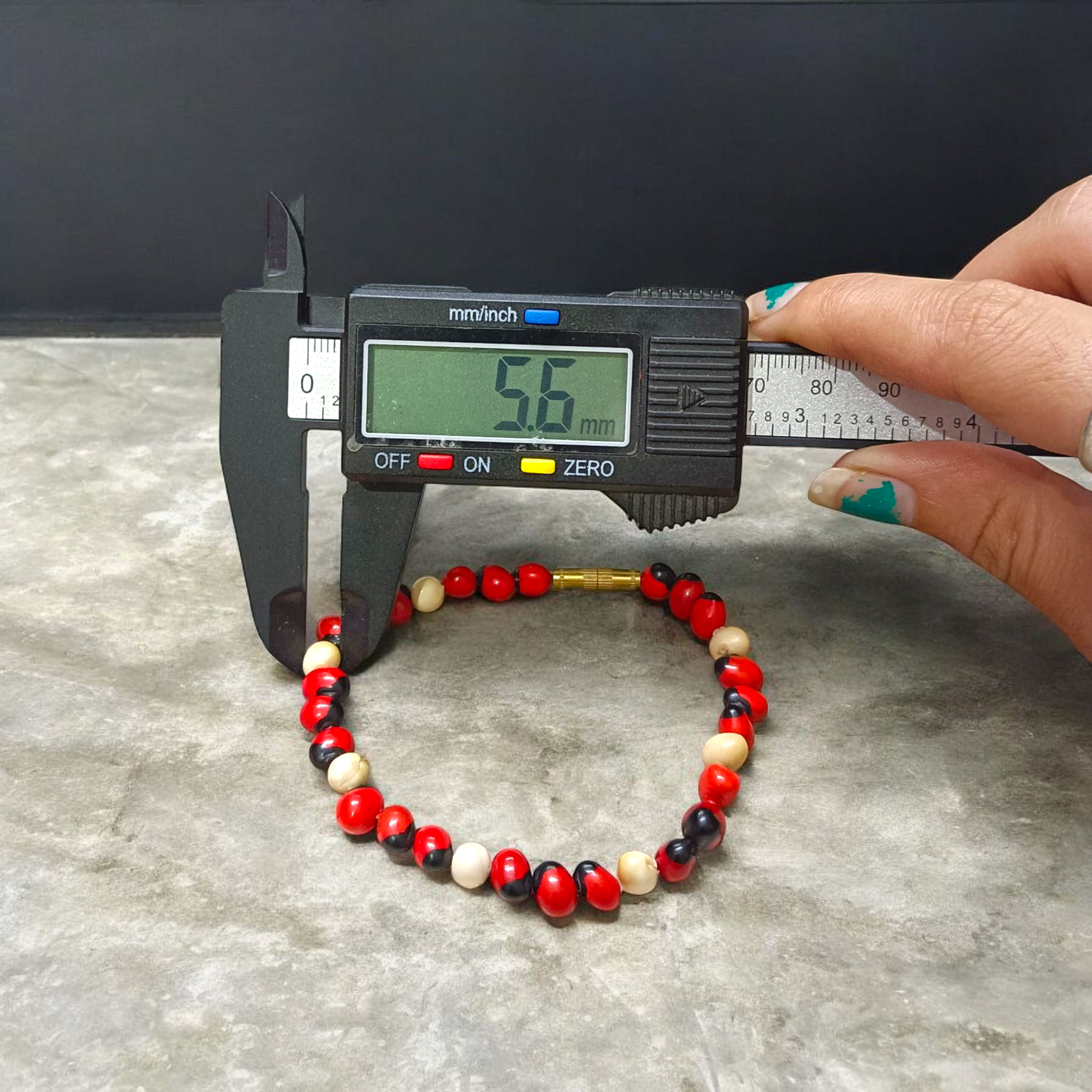 Natural Red and White Gunja seed bracelet with 5mm stretchable beads, spiritual design laid on a neutral background