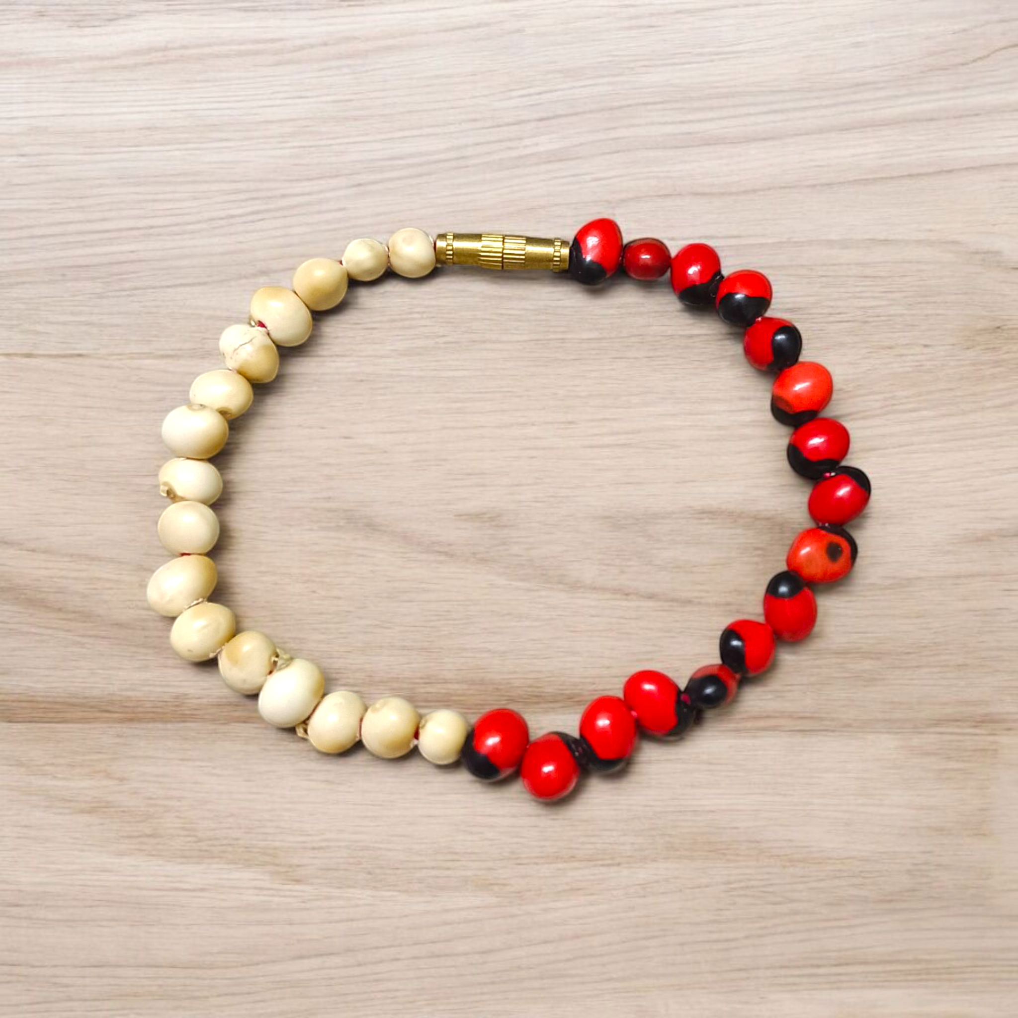 Natural Red and White Gunja seed bracelet with 5mm stretchable beads, spiritual design laid on a neutral background
