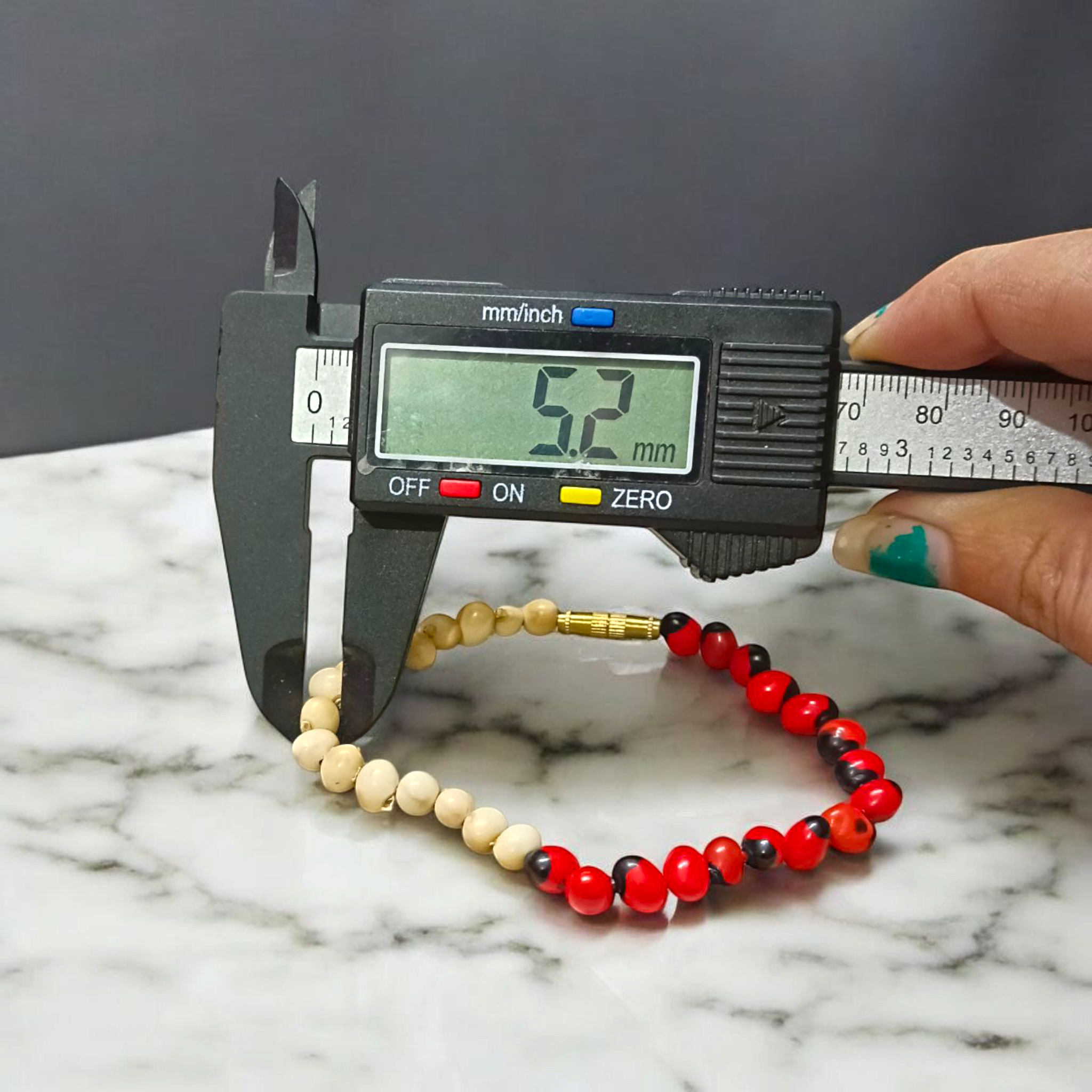 Natural Red and White Gunja seed bracelet with 5mm stretchable beads, spiritual design laid on a neutral background
