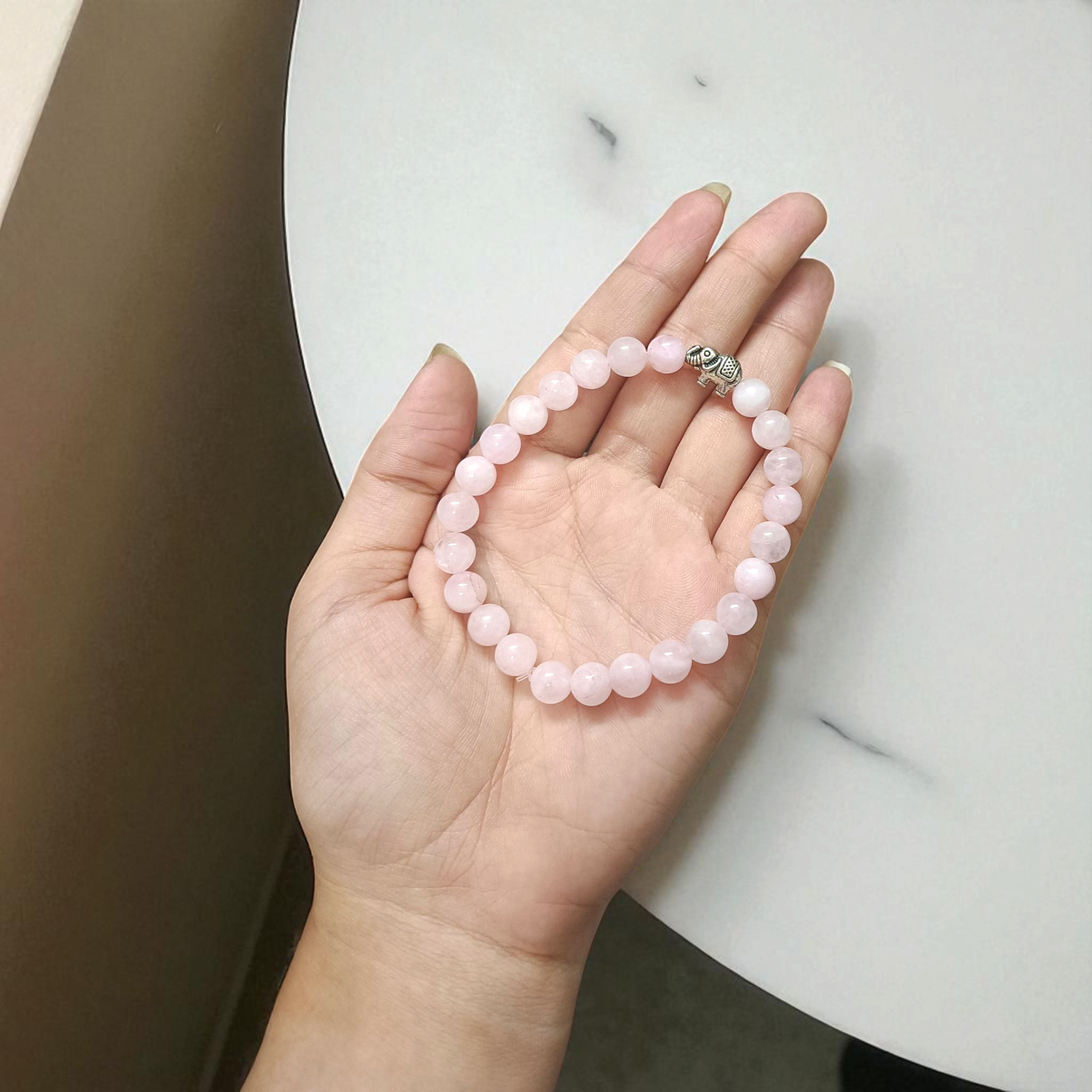 Natural Rose Quartz bracelet with 8mm round pink beads on a stretchable band, displayed on a clean white background