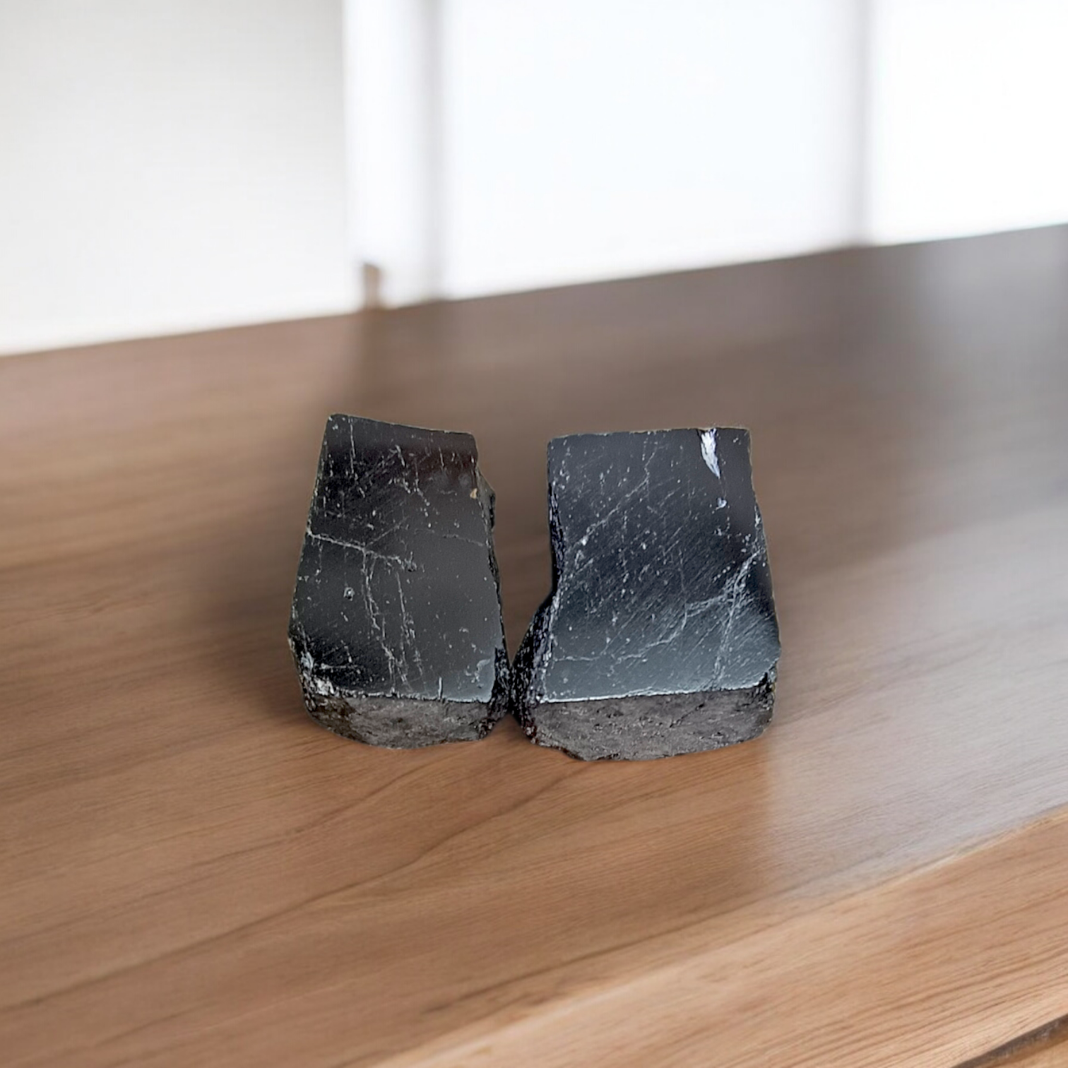 Two polished black Tourmaline stones with smooth texture, placed side by side, symbolizing protection, grounding, and Root Chakra energy