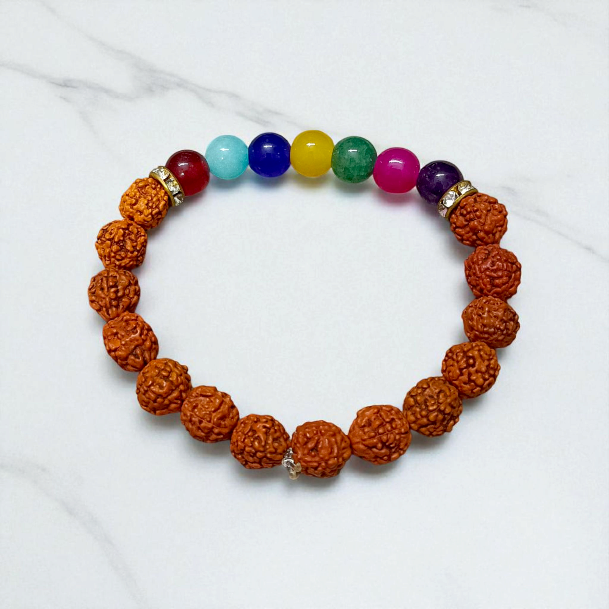 7 Chakra & Rudraksha Bracelet with 8mm natural beads, arranged in colorful chakra order alongside sacred Rudraksha beads, displayed on a spiritual setting