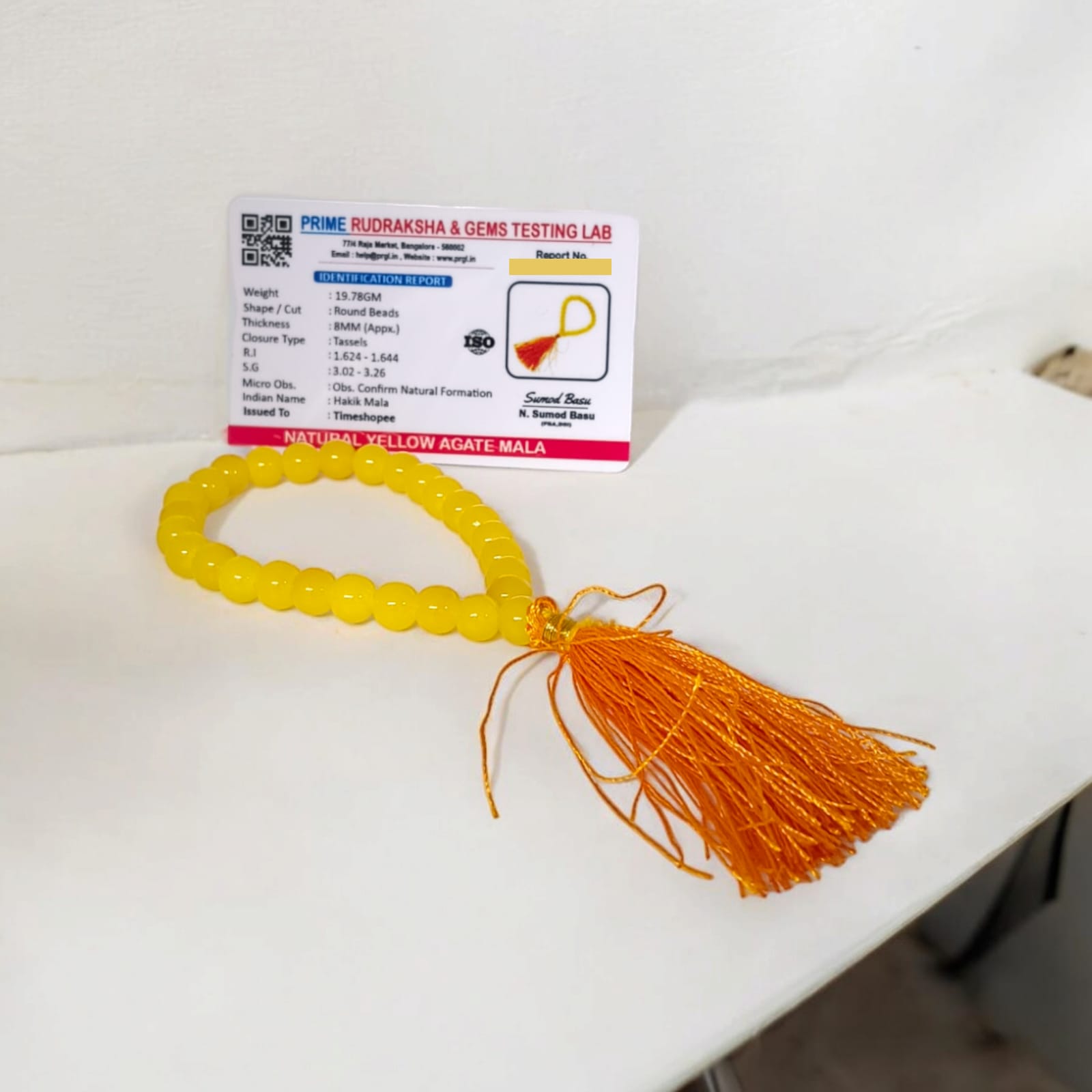 A 27+1 bead yellow agate mala, each bead measuring 8mm, displayed with its lab certification. The mala is ideal for wearing, meditation, or keeping in cars and offices.