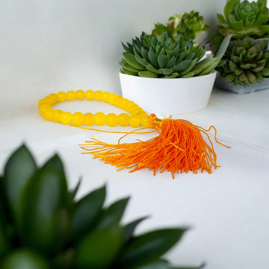 A Yellow Agate Mala with 8MM round beads in 108+1 bead count, hand-threaded and arranged neatly on a white surface, showcasing its golden hue and craftsmanship