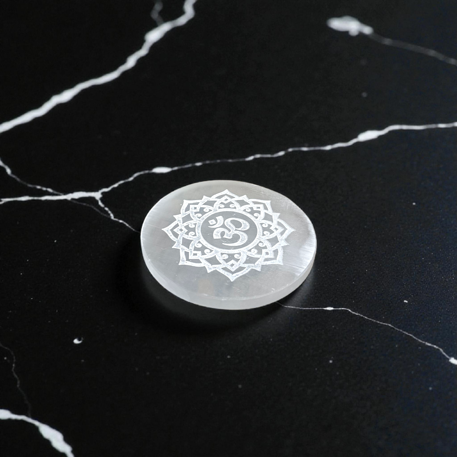 A polished round Selenite charging plate featuring a carved Om symbol, used for pooja, décor, and energy cleansing