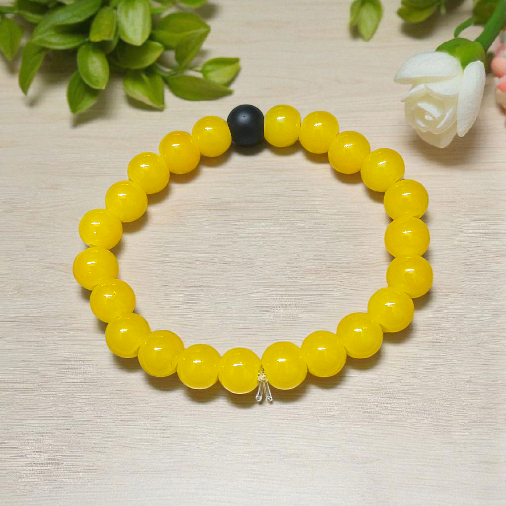 A stretchable Yellow Agate & Ebony Bracelet made with 8mm natural beads, placed neatly on a white cloth background