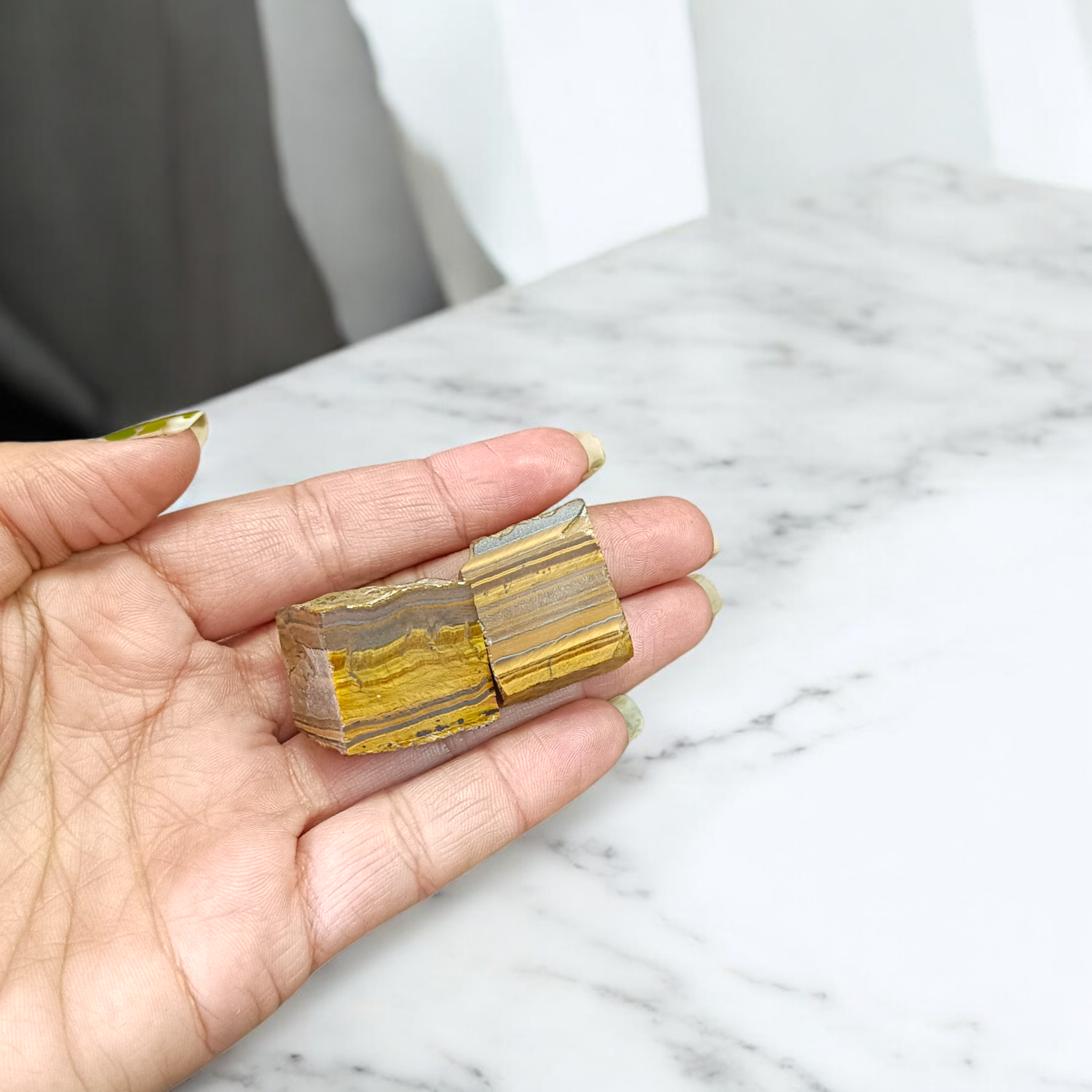 Two polished golden-brown Tiger Eye stones with smooth texture, placed side by side, reflecting natural shimmer and grounding energy